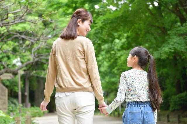 障害を持つ子供と手をつなぐ母親