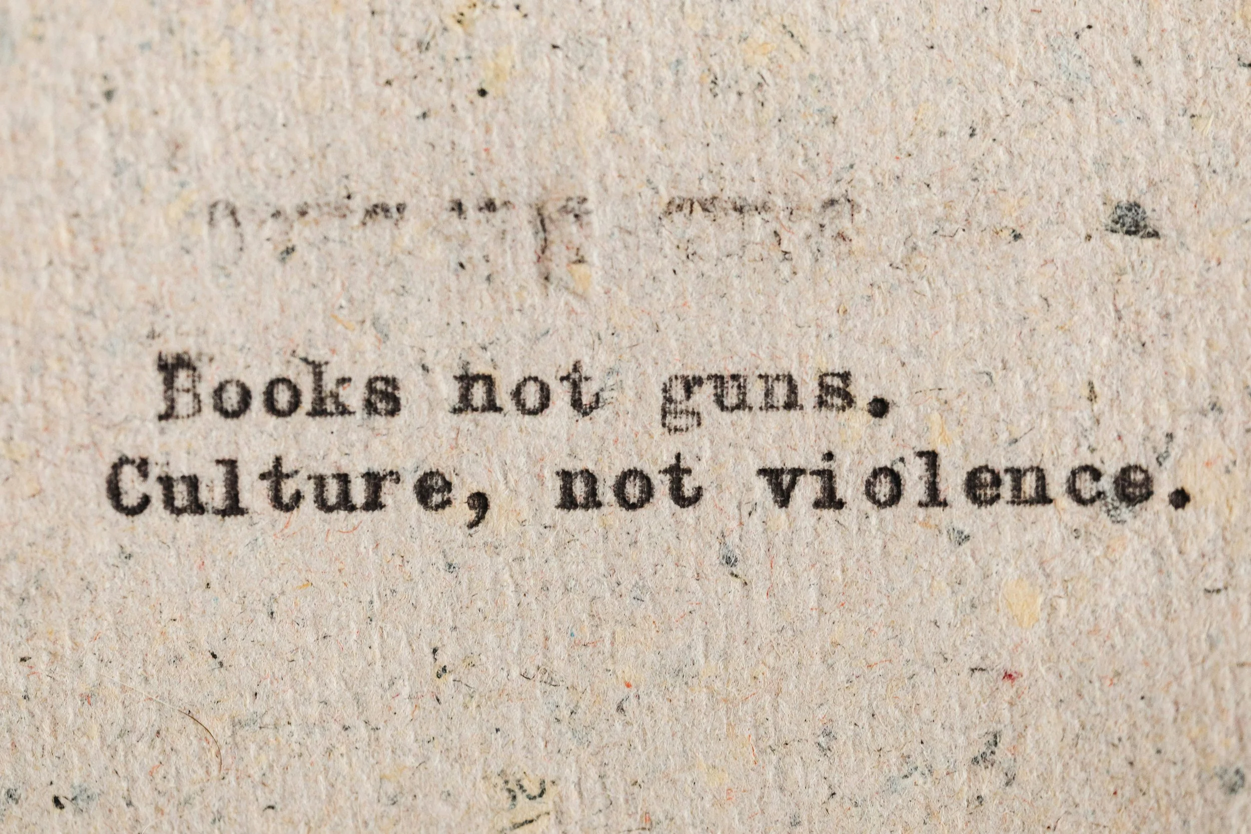 Close-up of a printed quote on textured paper that says, 'Books not guns. Culture, not violence.'