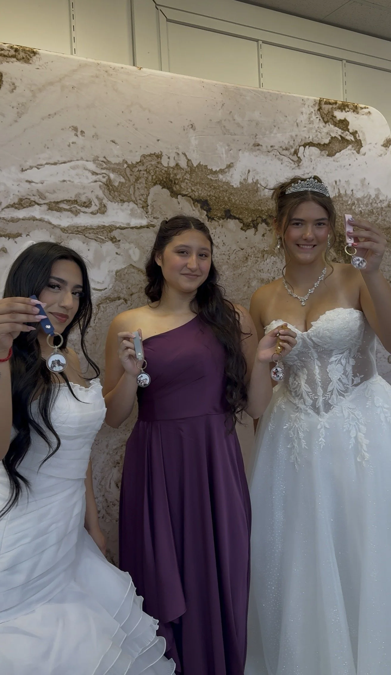 Wedding and quinceañera guests holding personalized acrylic photo keychains from Luna Event Rentals photo booth upgrade in Tri-Cities WA