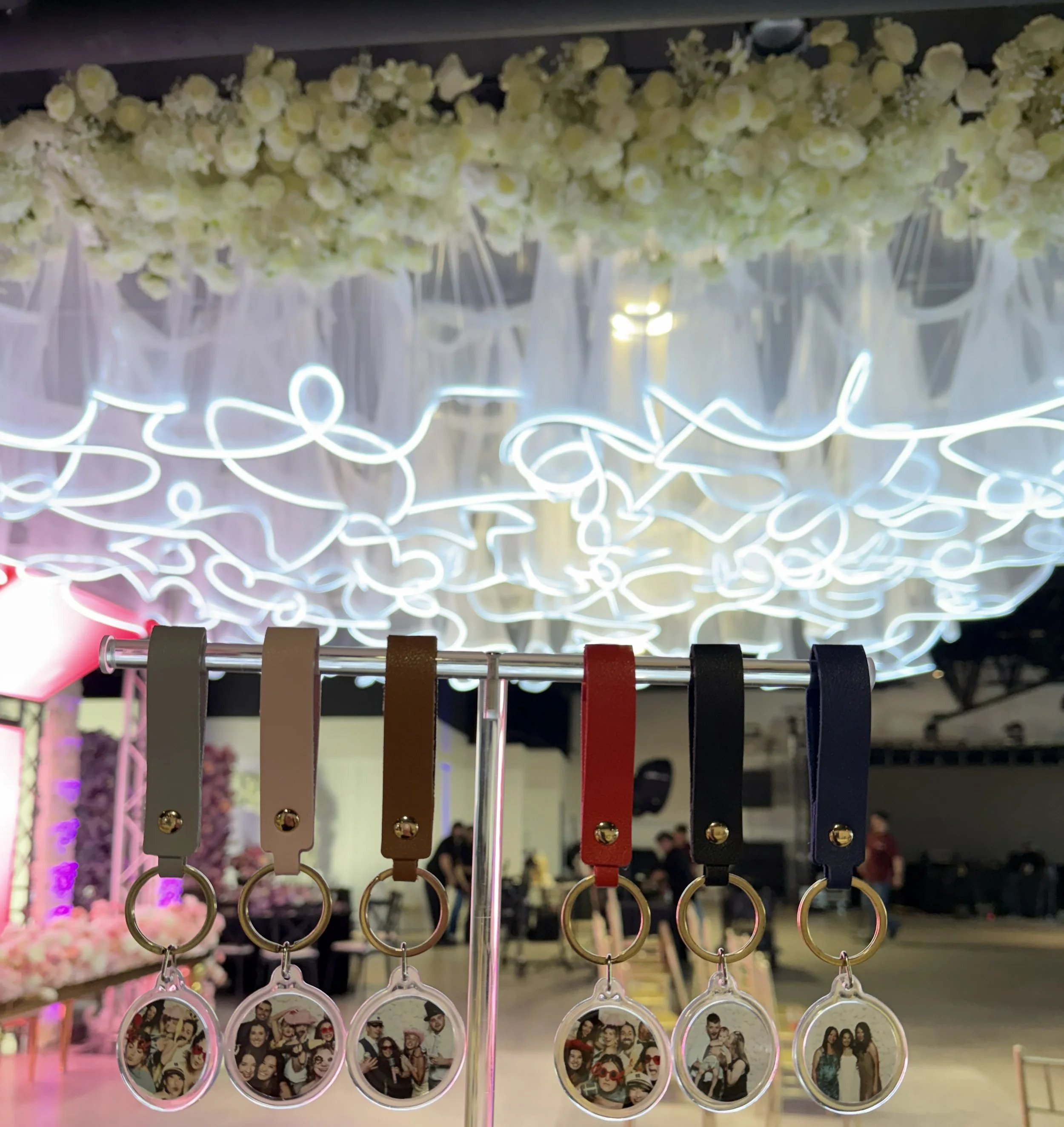 Personalized acrylic photo keychains with leather straps displayed on rack at quinceañera event by Luna Event Rentals in Tri-Cities WA