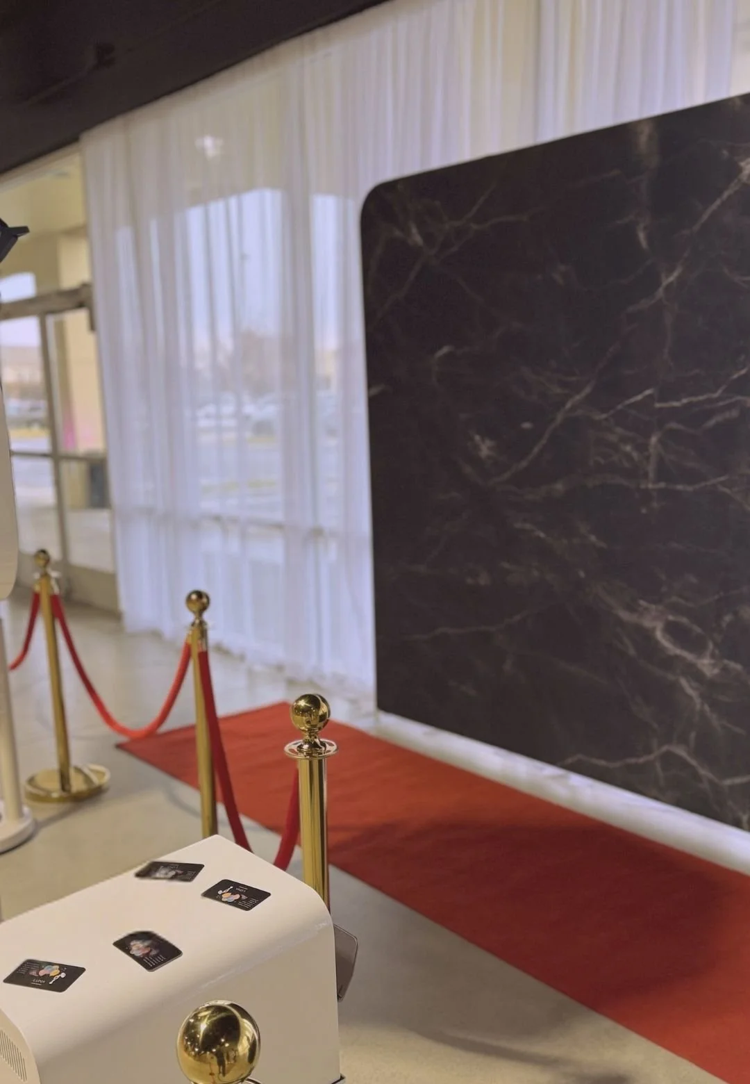 Luxury photo booth rental with red carpet, gold stanchions, and black marble backdrop for corporate events, weddings, and upscale celebrations