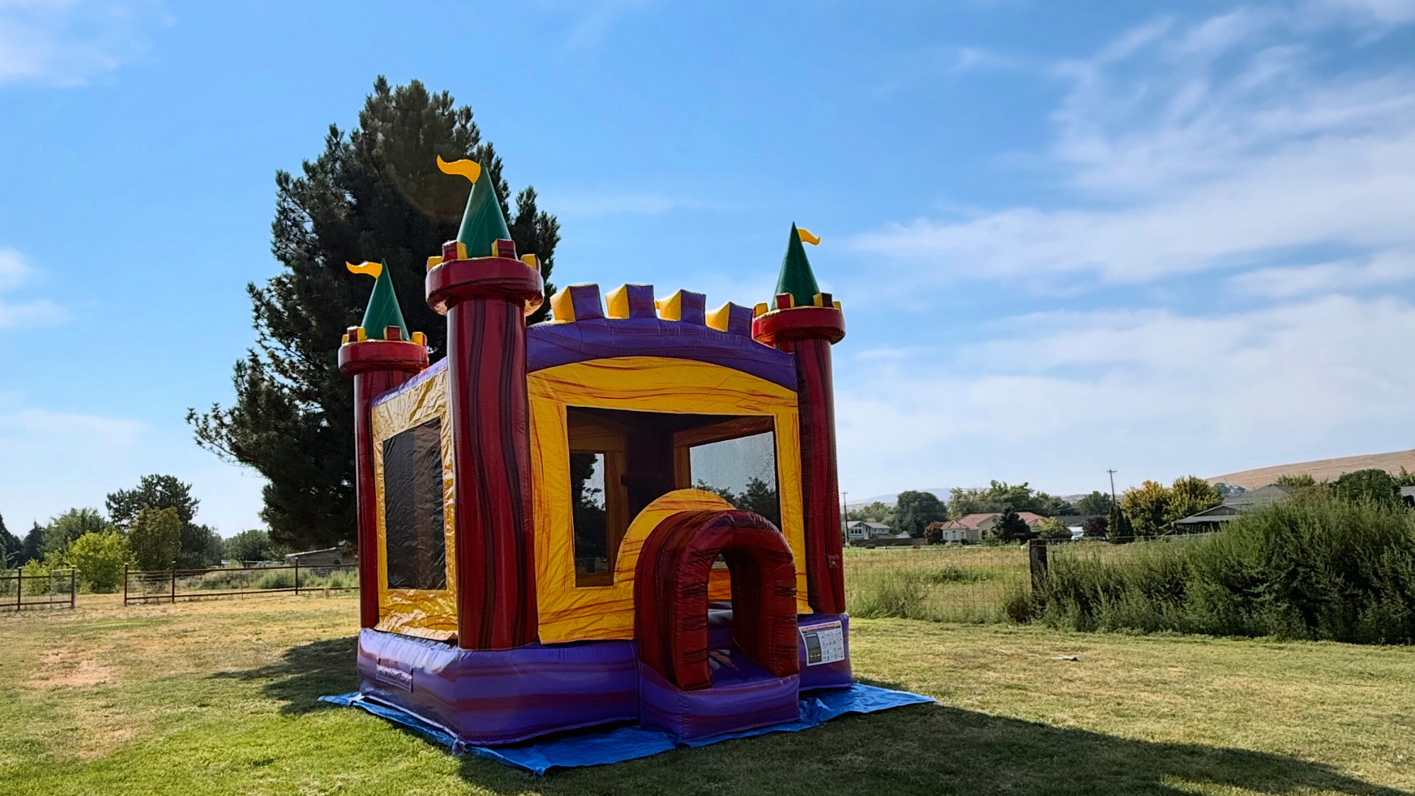 Red yellow and purple castle bounce house rental set up on grass for a kids party in Tri-Cities WA by Luna Event Rentals