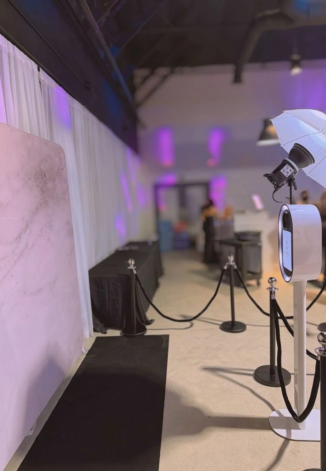 Luxury photo booth rental setup with black carpet, stanchions, and modern backdrop for corporate events, private parties, and upscale celebrations