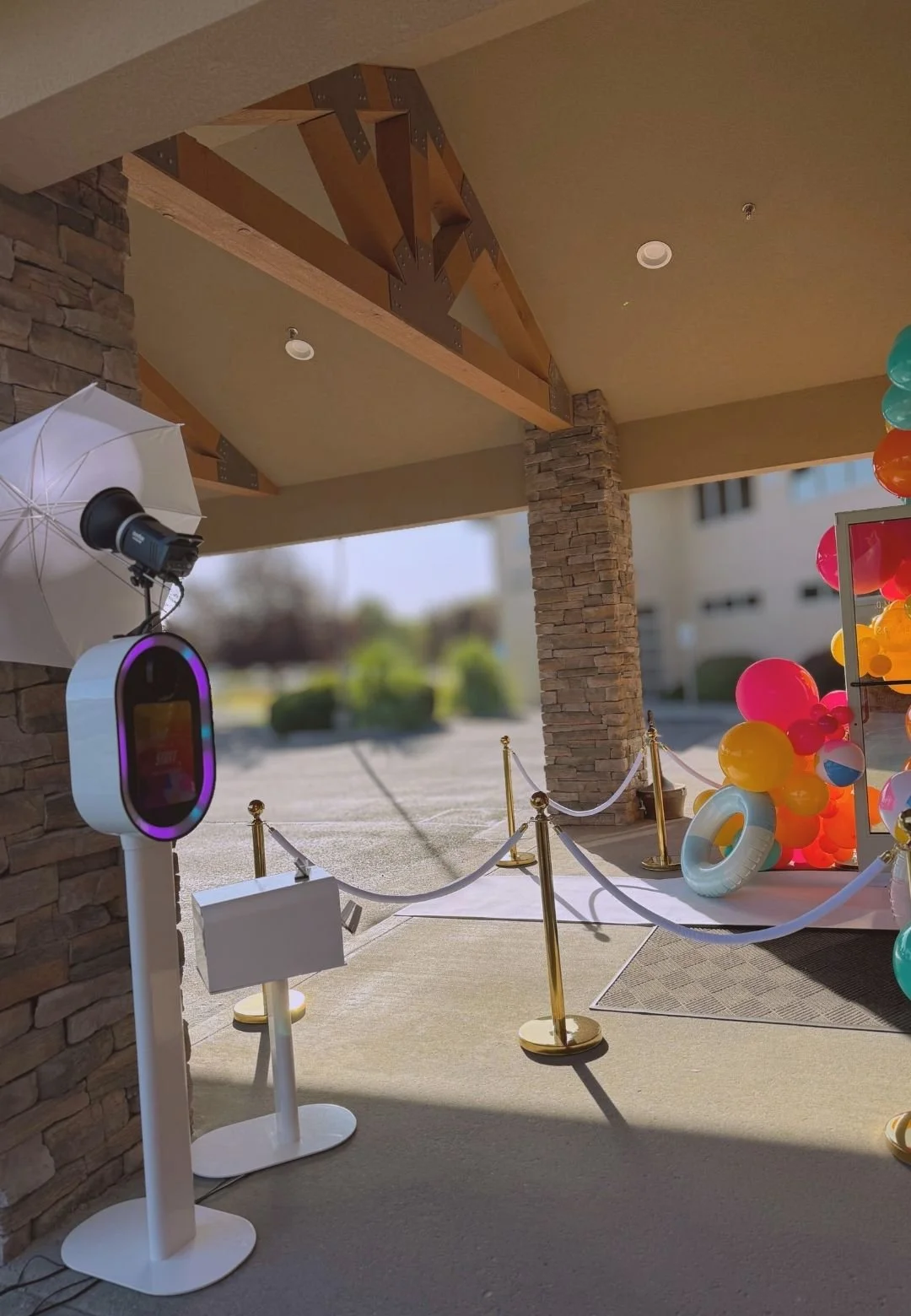 Outdoor open air photo booth rental with gold stanchions and colorful balloon display at event in Tri-Cities WA by Luna Event Rentals
