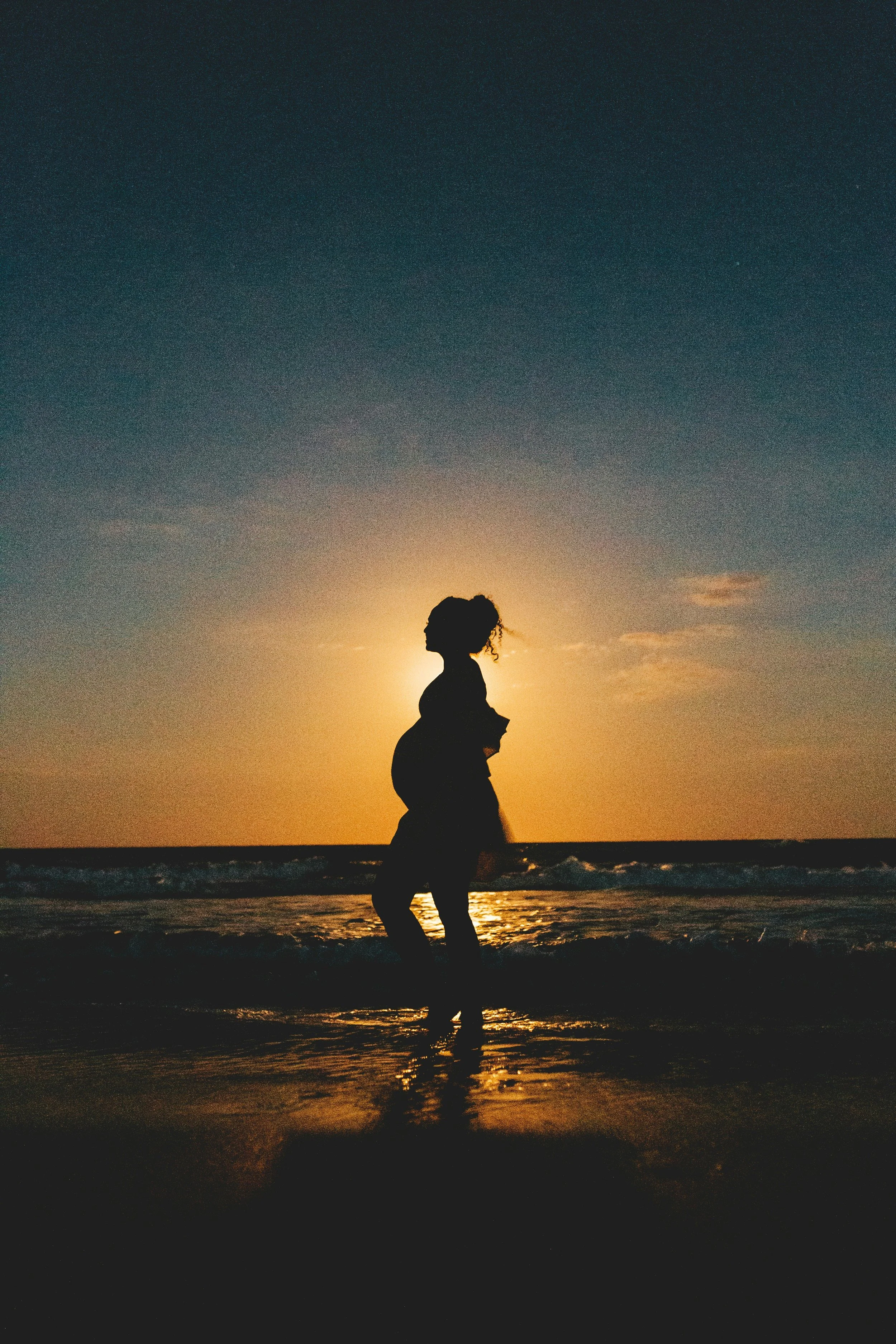 A woman standing at the beach in Humboldt County basking in her baby and pregnancy