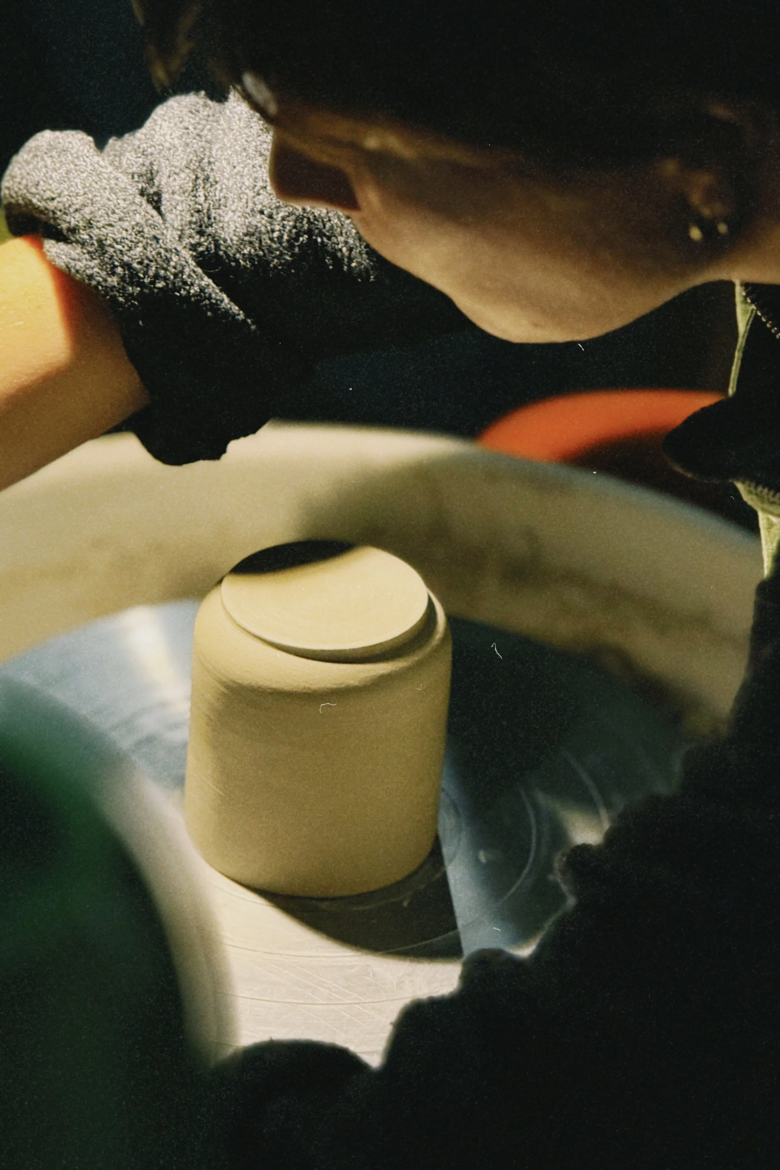 Personne en train de façonner ou de polir un objet en céramique ou en argile sur un tour de potier, en se concentrant sur le travail manuel.