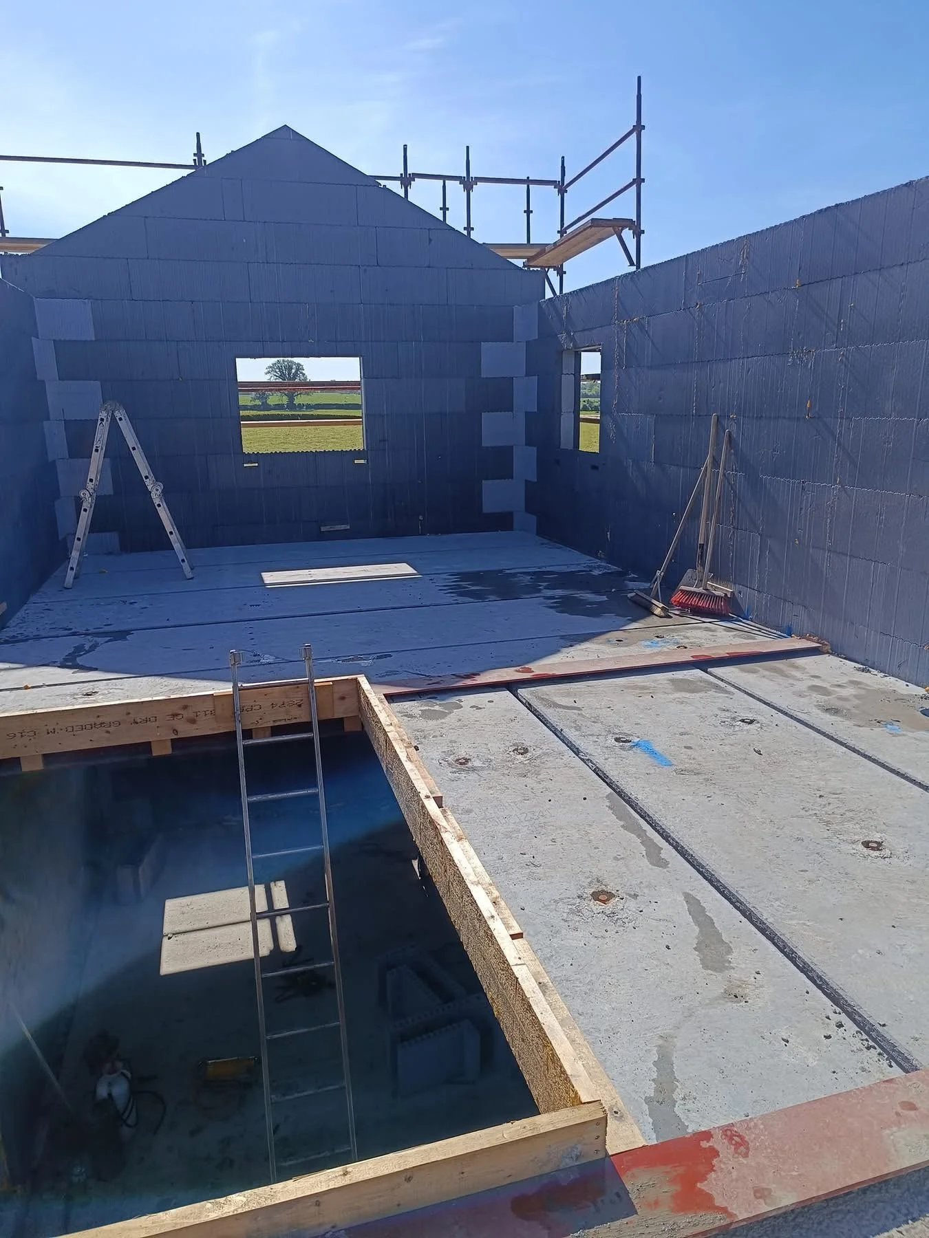Construction site of a building with ICF walls, windows, and a roof. Scaffolding around the roof.