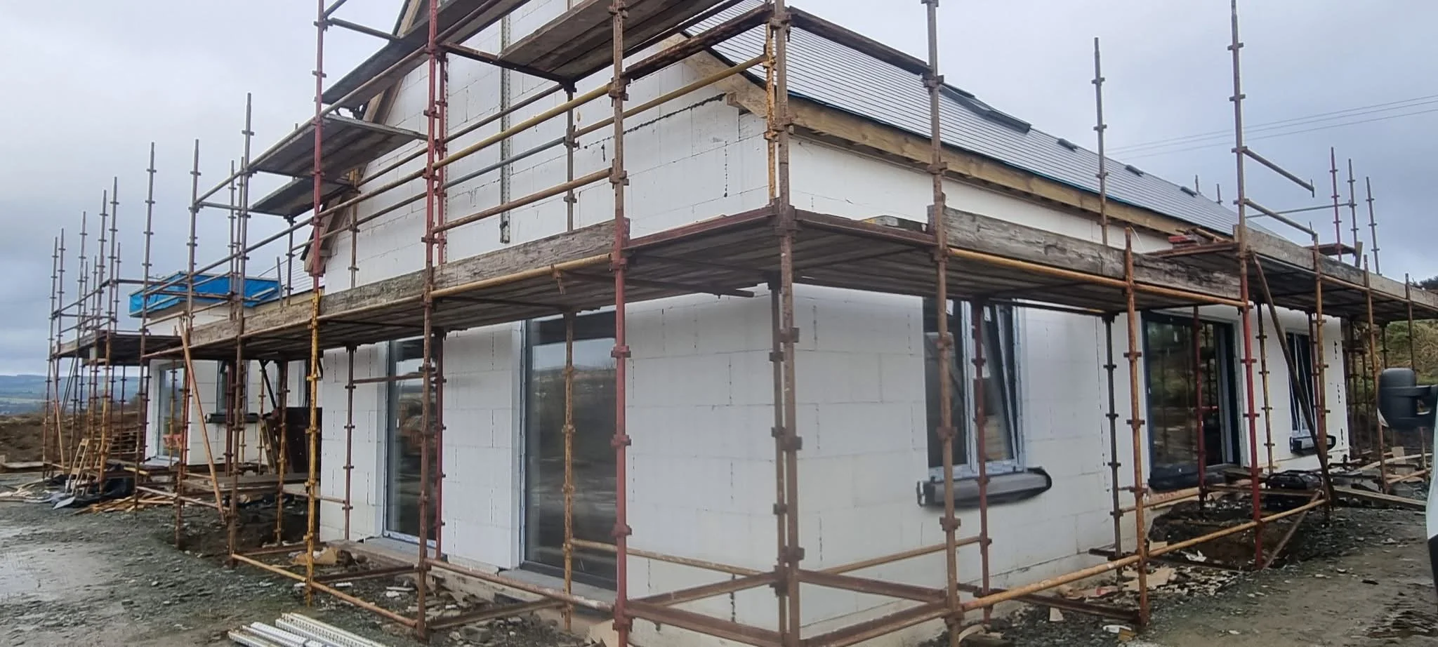 Construction of a two-story building with ICF walls, large windows, and scaffolding surrounding the structure. The building is ready for render application