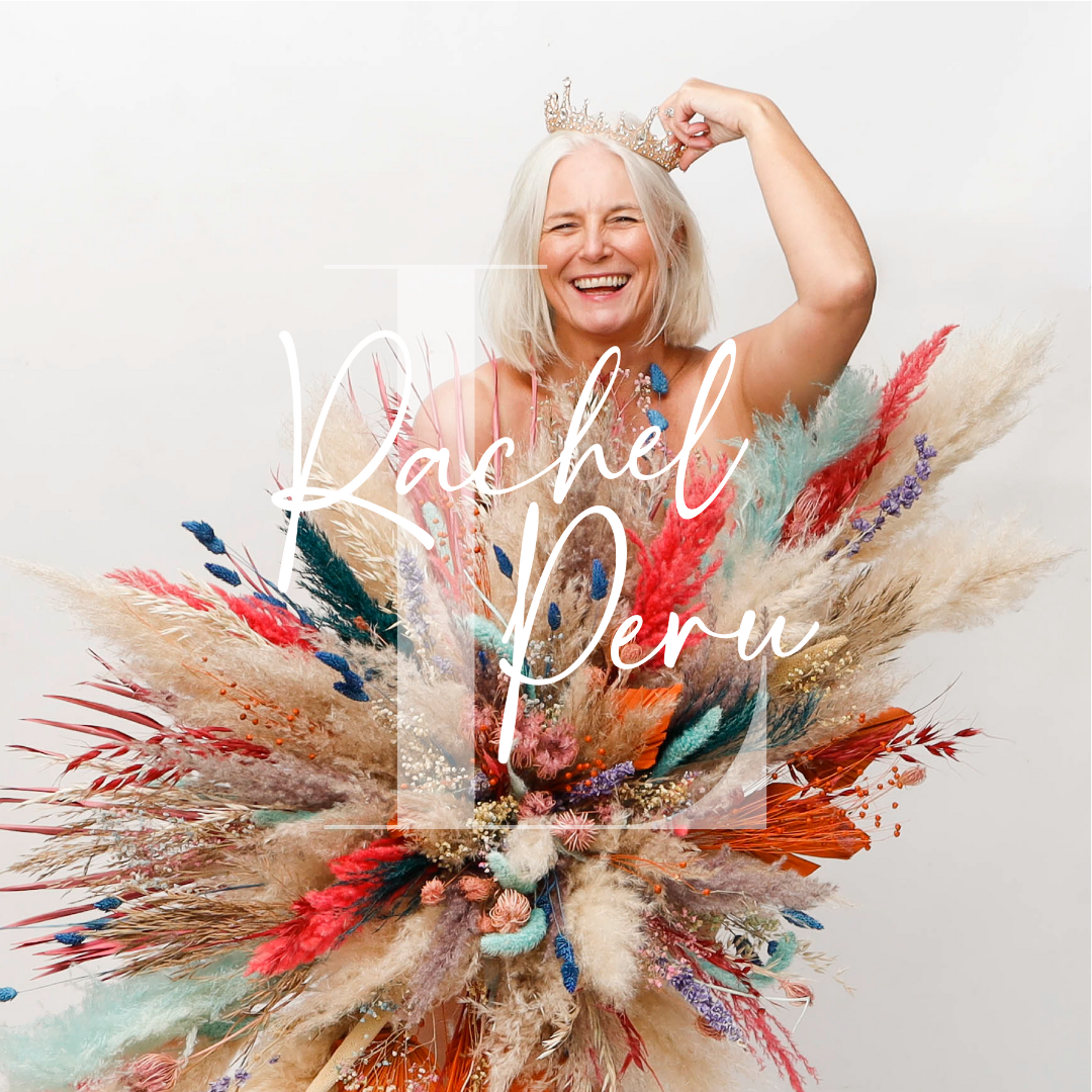 A woman with gray hair smiling, wearing a crown, holding her arm above her head, surrounded by a large bouquet of colorful dried flowers and grasses, with the overlay text 'Rachel Peru' in white cursive.