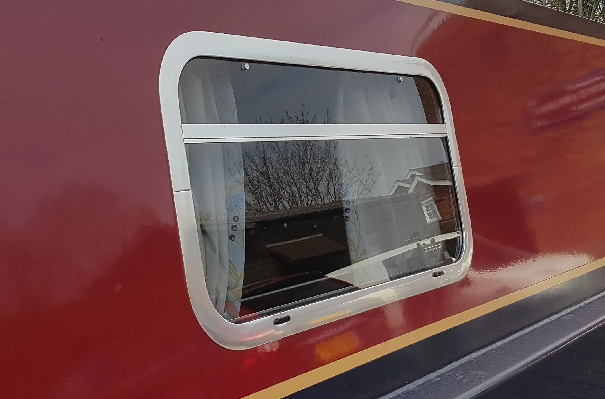 Bespoke SX type window on the side of a red narrowboat.