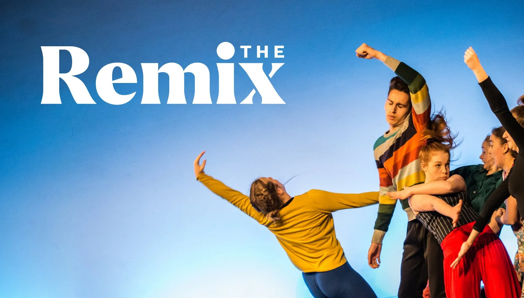 Group of people dancing and posing on stage with a blue background, with the text 'The Remix' in the upper left corner.