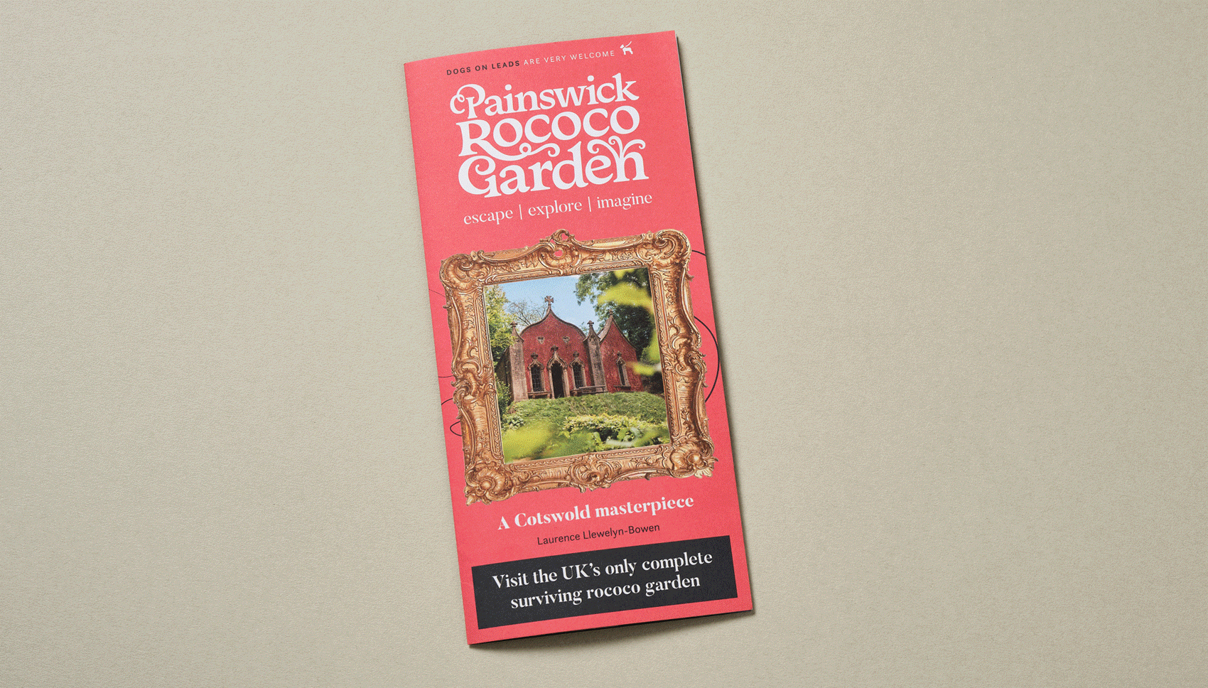 Pink brochure titled 'Painswick Rococo Garden' with an ornate gold frame around a photo of a red brick rococo-style building with arched windows, surrounded by greenery, and text indicating it is a Gotswold masterpiece with a subtitle inviting visitors to explore the UK's only surviving rococo garden.