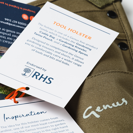 Close-up of a brown garden tool bag with a tag describing a tool holster endorsed by IRHS. The tag explains the holster is made for carrying gardening tools and accessories, designed for comfort and ease of use. Part of another product tag and a small orange detail are also visible.