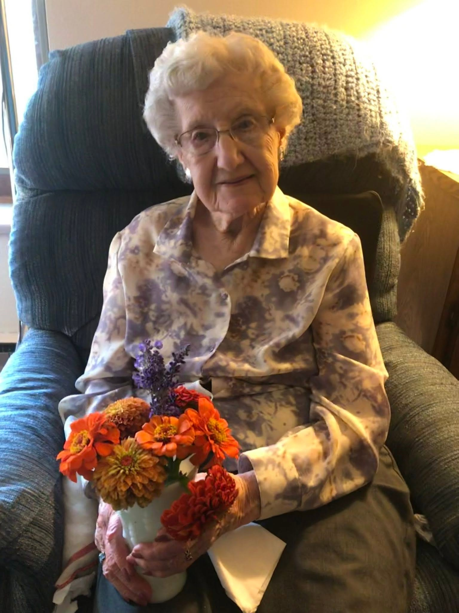 Clarice seated with a bouquet of orange flowers