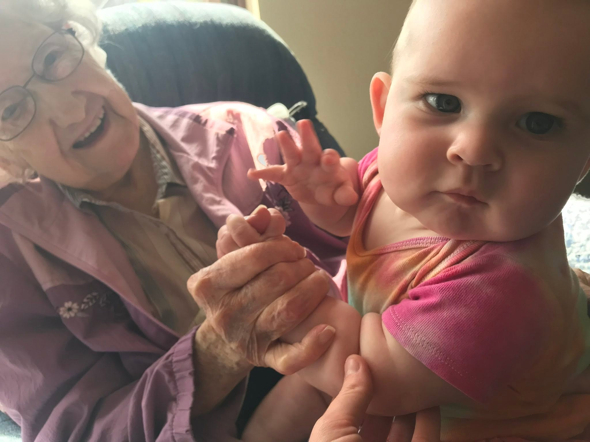 Clarice smiling as she holds a baby’s hand