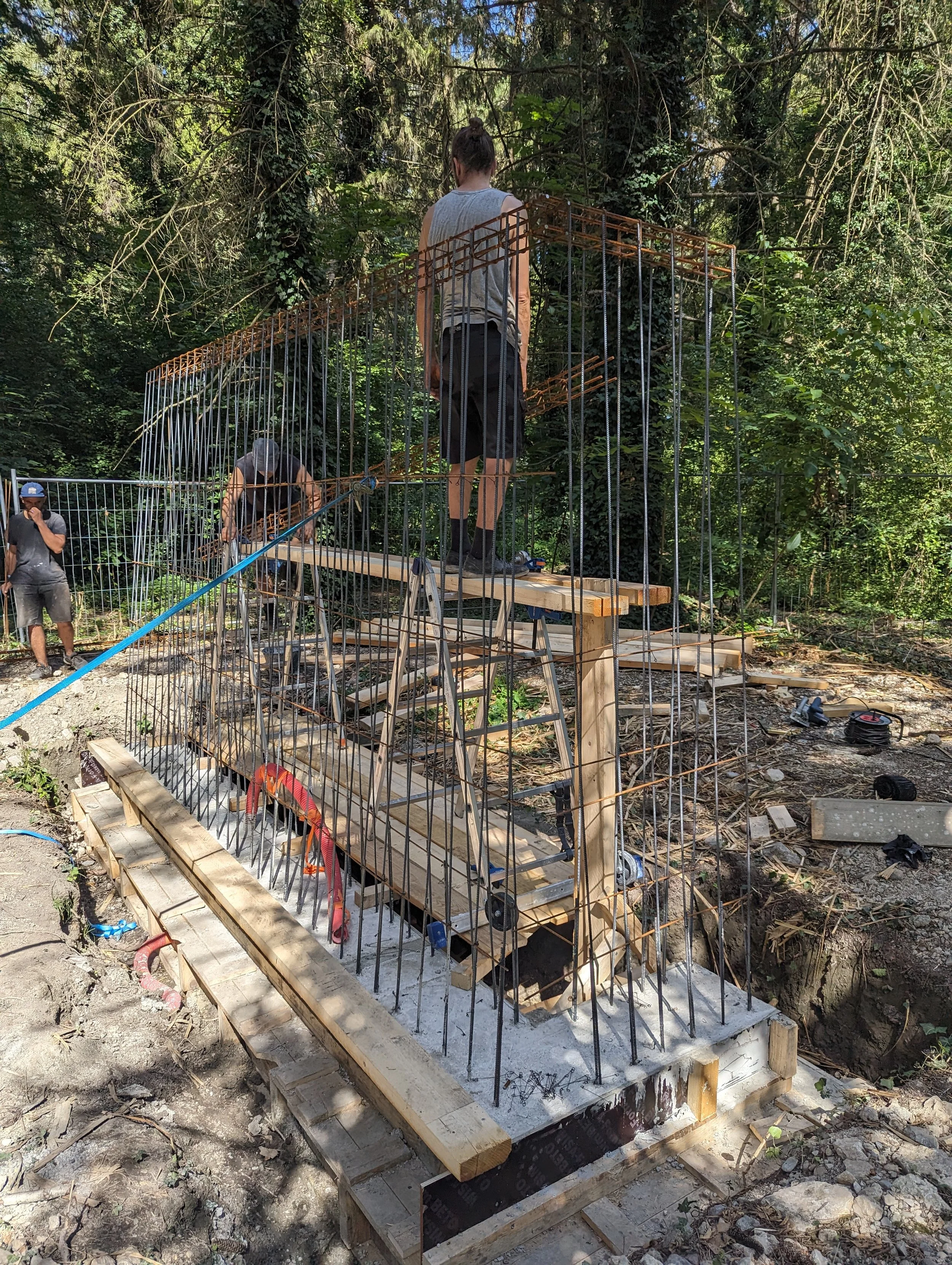 Élaboration de fondation avec une structure en métal dans lequel va être coulé du béton, dans une forêt avec des travailleurs de l'atelier pour l'installation intitulée" Vestiges" d'Hicham Berrada.
