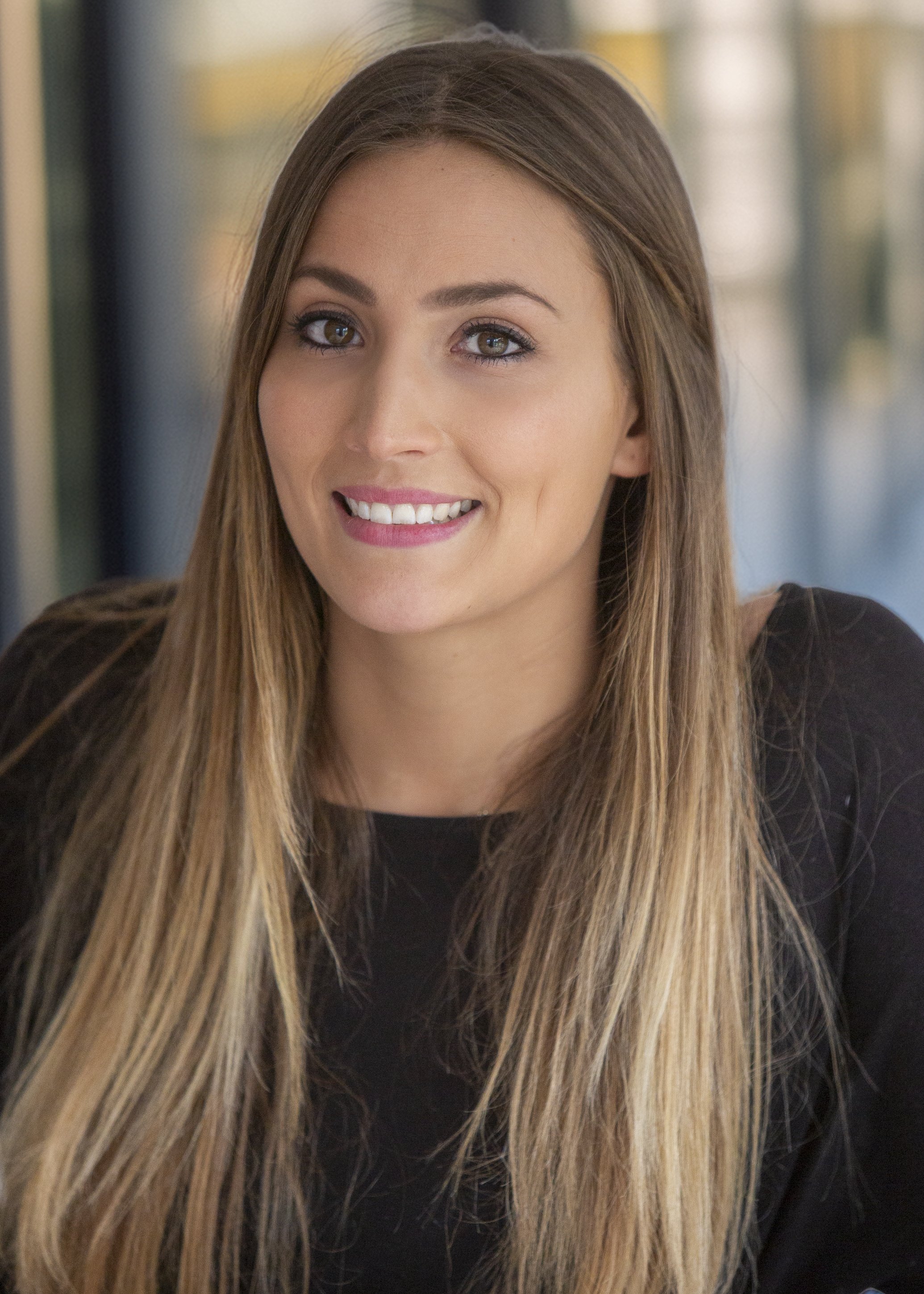 A young woman with long, light brown hair, light skin, and a bright smile.