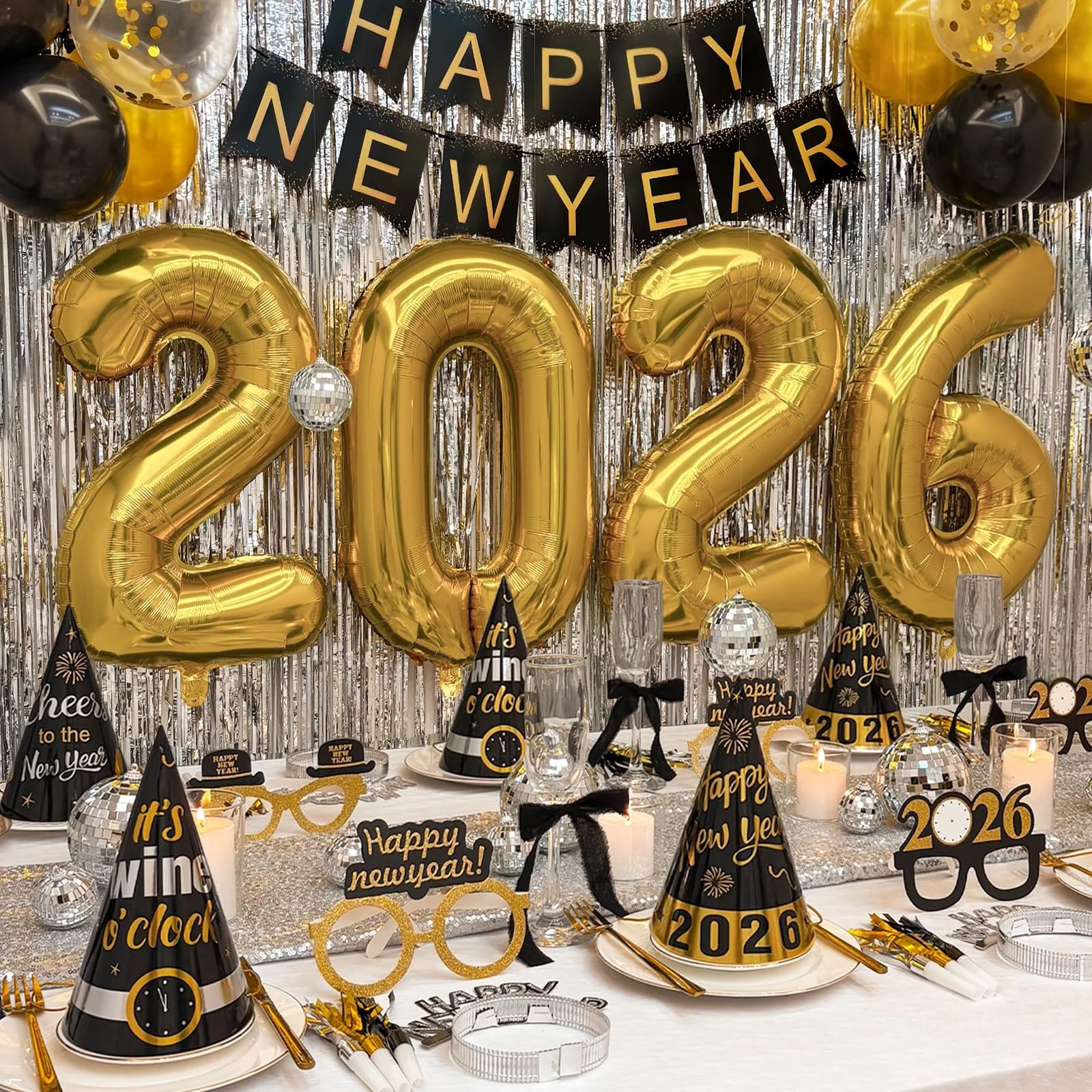 Golden 2026 set up, with large balloons, party hats on the table with paper prop glases, disco ball all in a celebration theme.