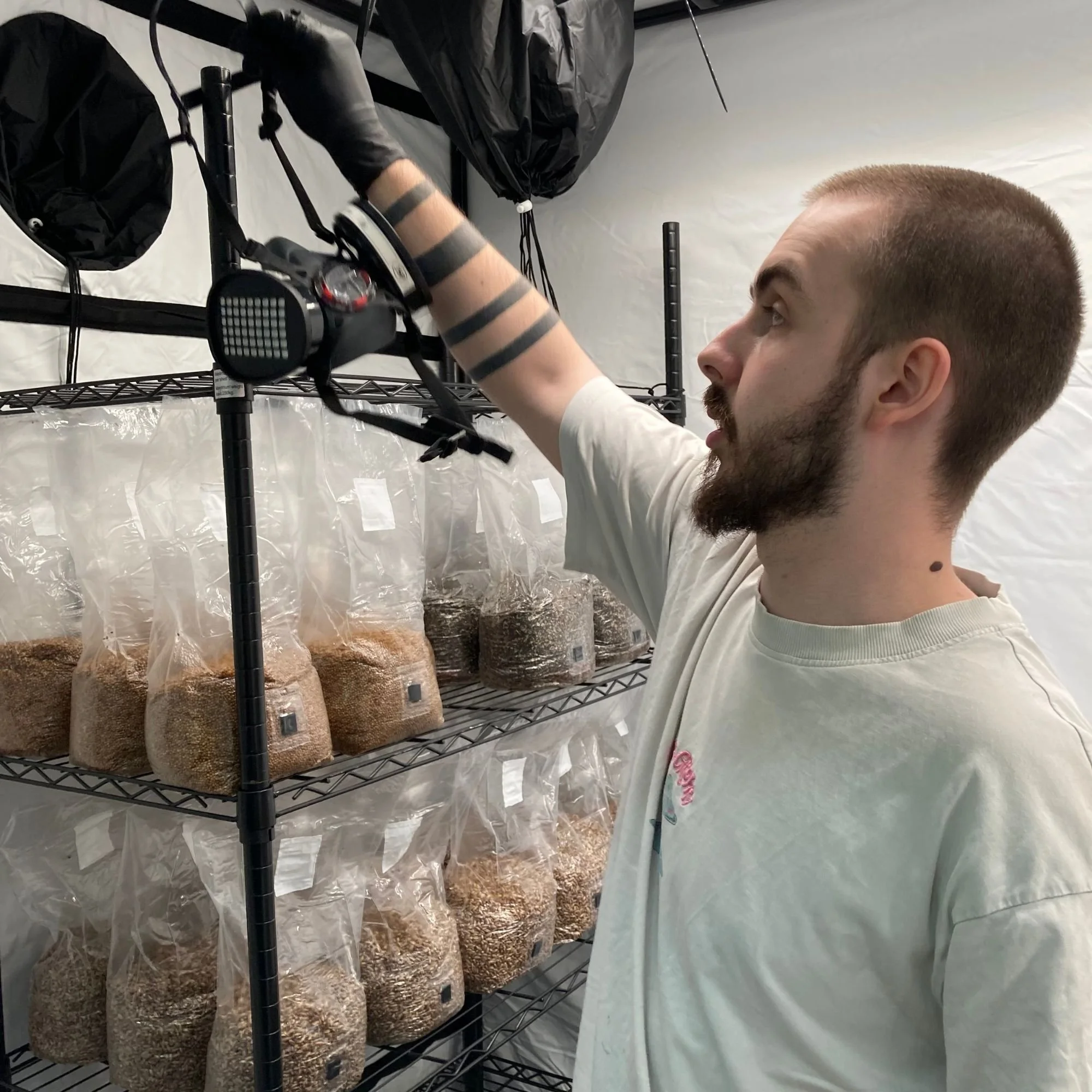 Louis Philogene-Cummings holding a mask with sterile grain bags in the background on racking