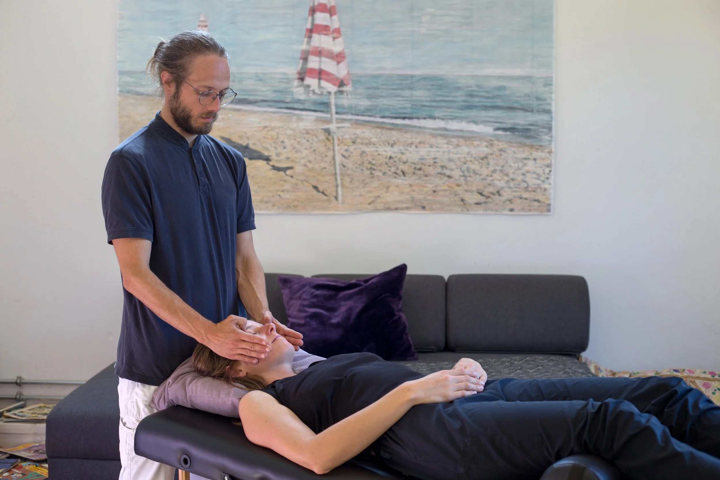 Ein Mann führt eine Massage an einem liegenden Mädchen in einem Wohnzimmer durch.