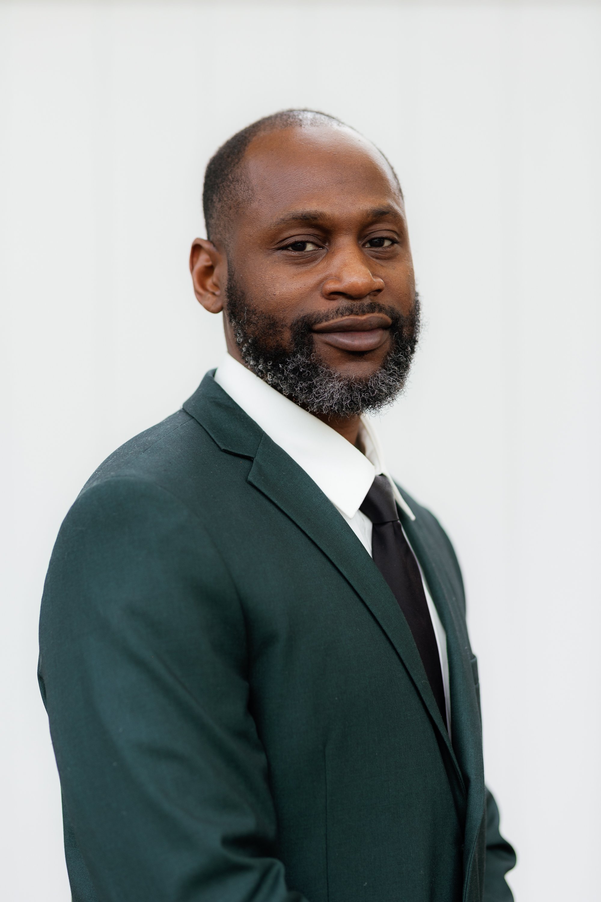 A professional man in a suit looking at the camera with a neutral expression.