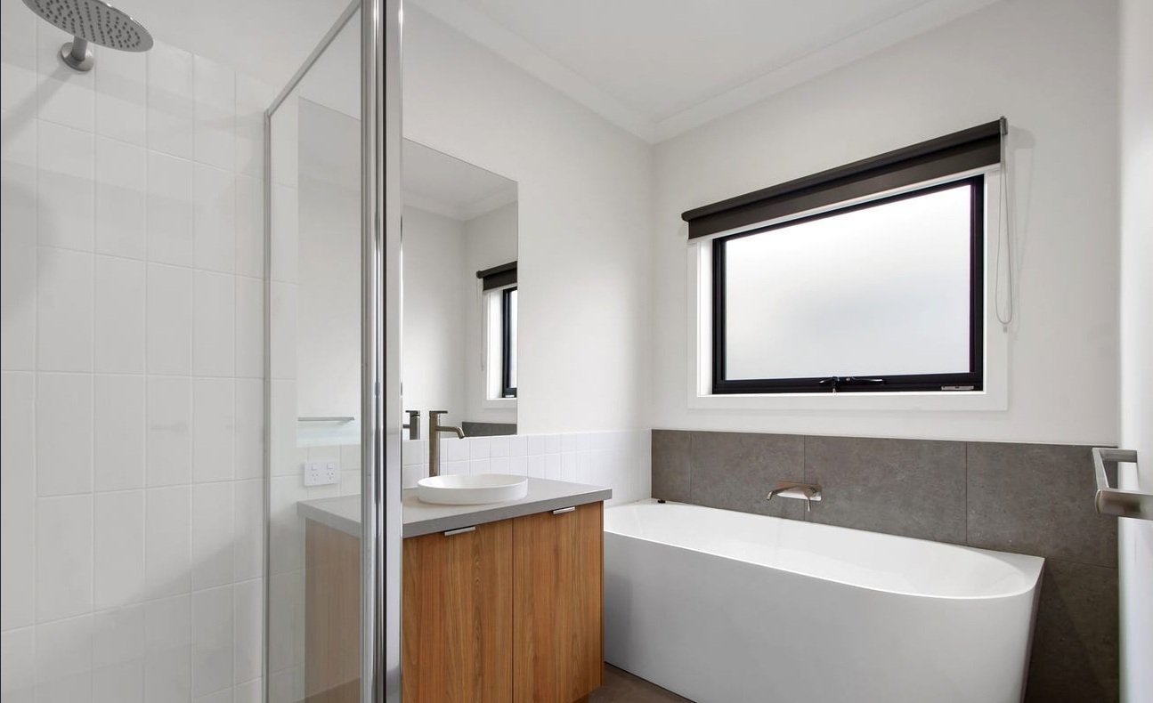 Modern bathroom with a freestanding bathtub, a vanity with a vessel sink, a large window with a black frame, and a glass shower enclosure.
