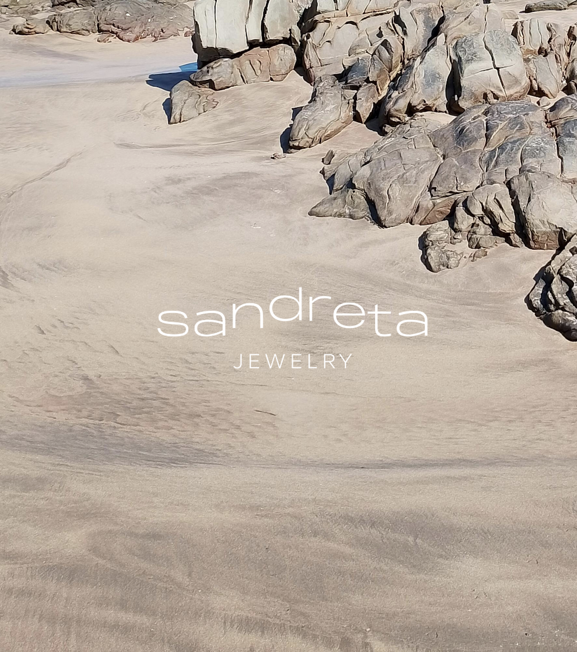Une plage de sable avec des rochers en arrière-plan, zoom avant sur le logo 'Sandreta Jewelry'
