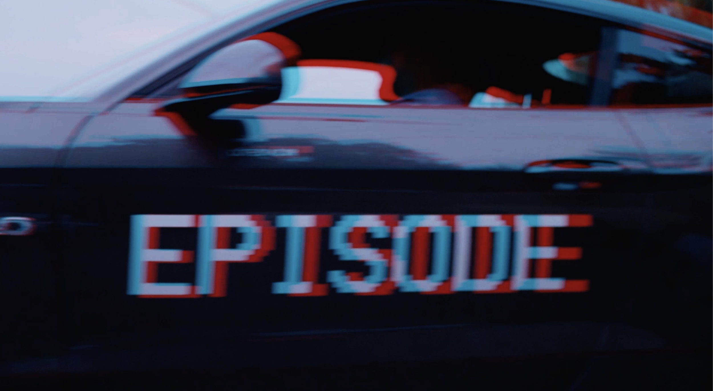 Voiture noire avec un panneau lumineux indiquant le mot « EPISODE » en lettres rouges et bleues floues