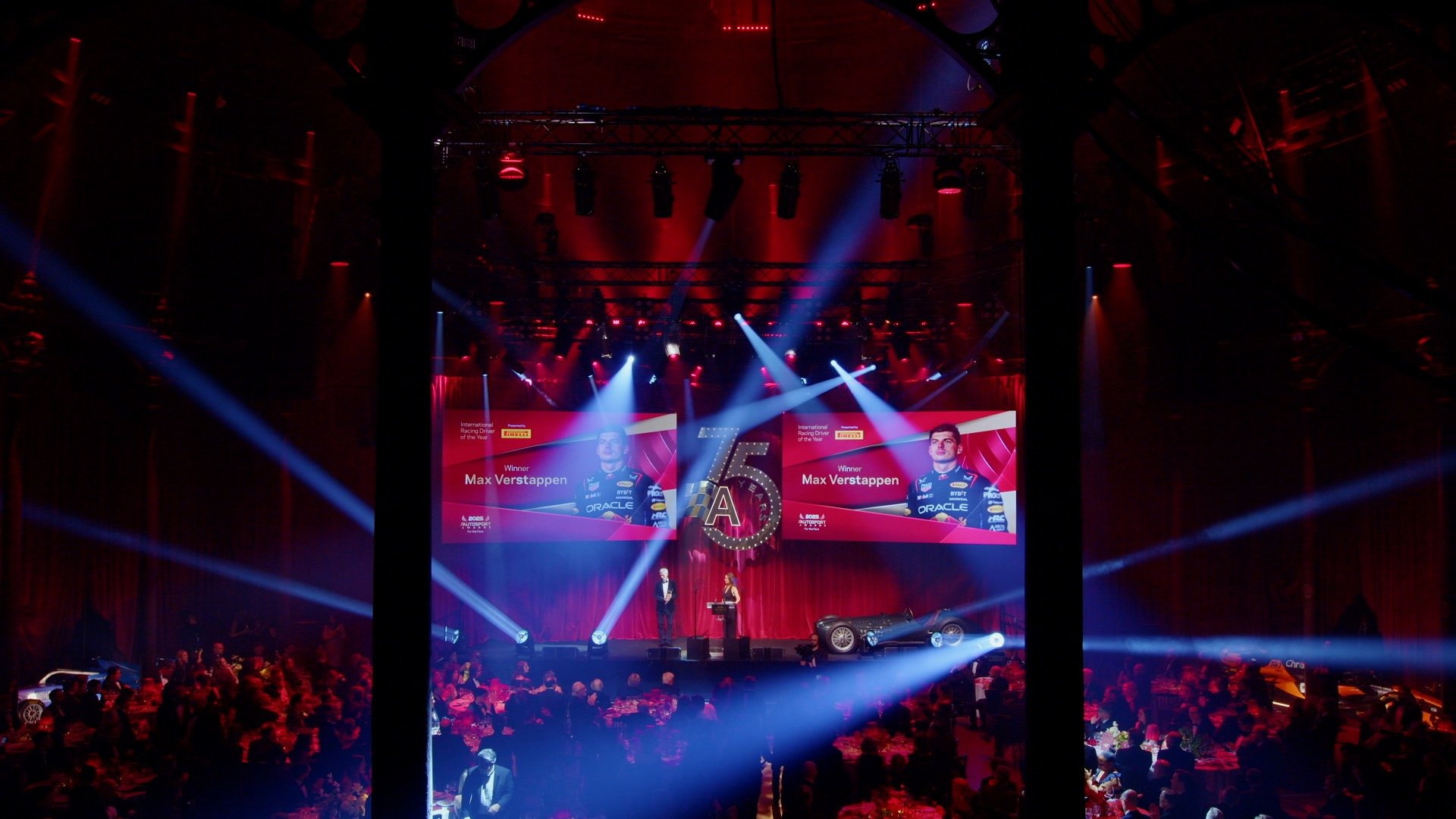 A person is filming a purple futuristic concept car with a professional camera mounted on a rig inside a studio.