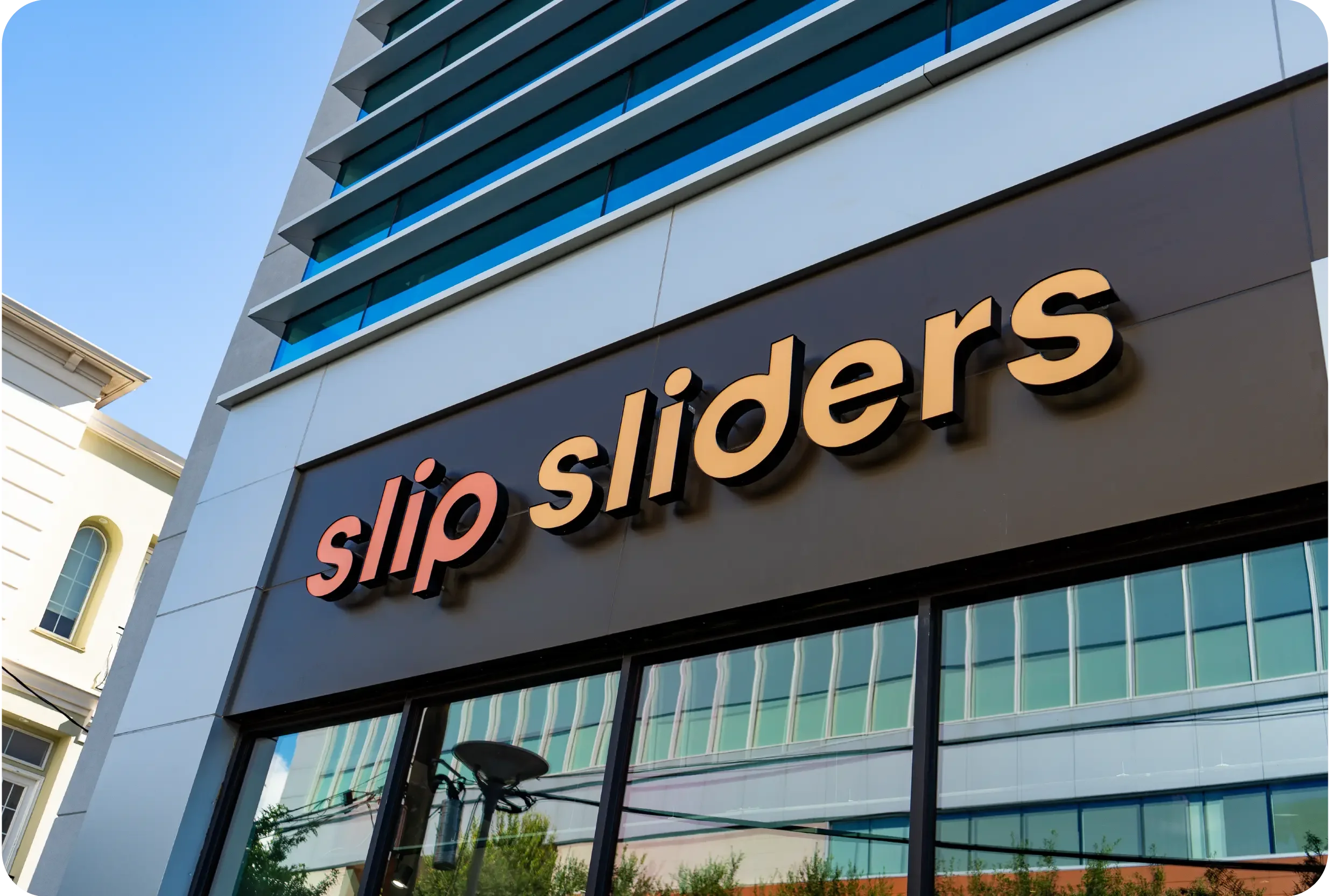 Exterior of Slip Sliders in Houston’s Museum District with dimensional, internally illuminated channel letter signage, glass windows, and wood facade.