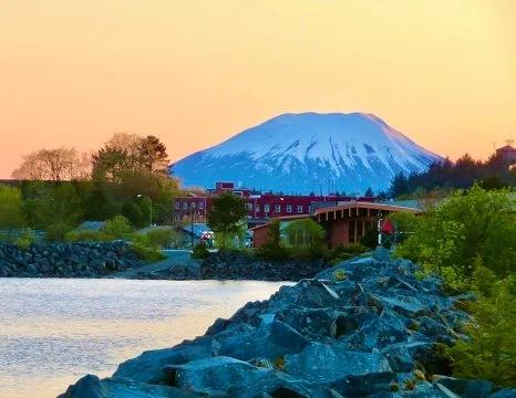 Scenic view of Mount Fuji with a river and greenery in the foreground during sunset.