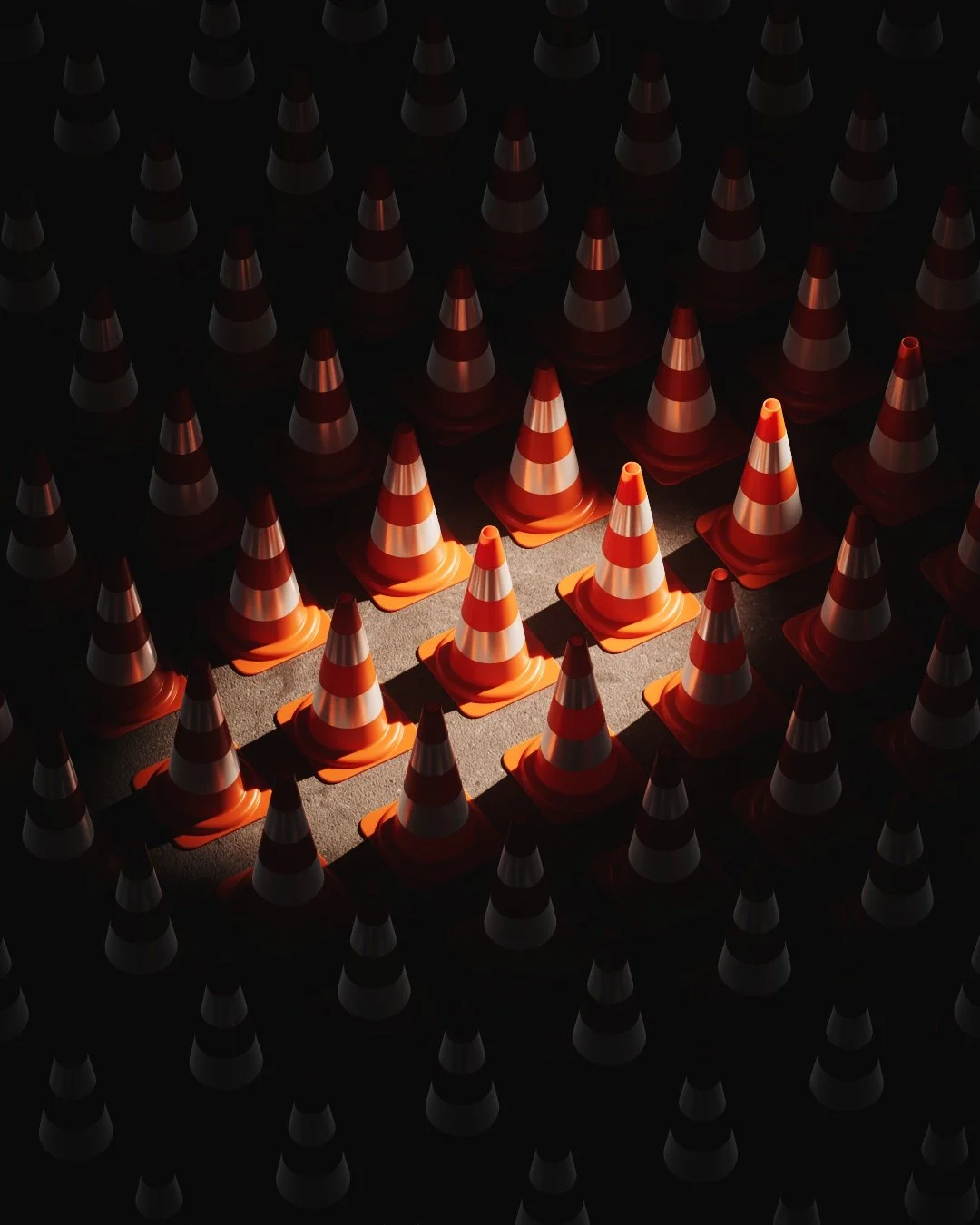 Numerosi coni stradali arancioni con riflessi bianchi su una superficie scura, con uno strato di luce che ne evidenzia alcuni.