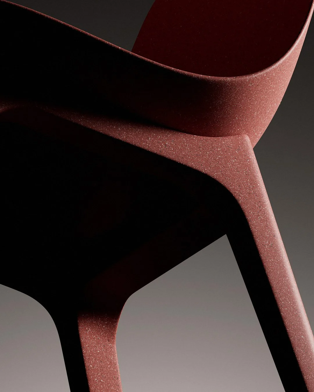 Dettaglio di una sedia moderna di colore rosso con finitura a superficie leggermente testurizzata, gli angoli arrotondati e le linee curve