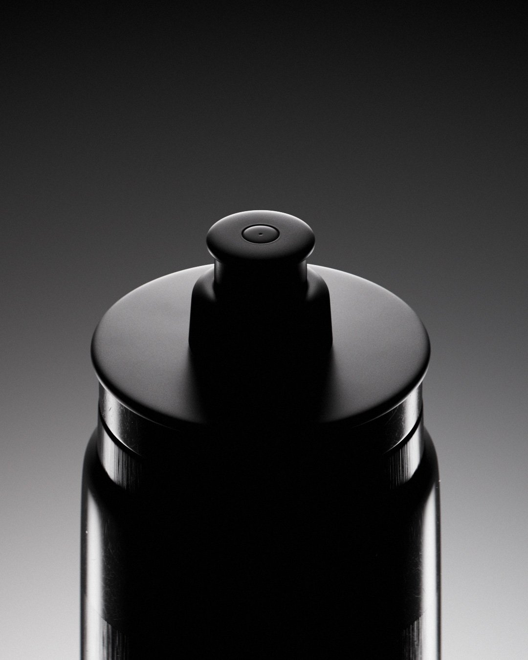 Dettaglio di un contenitore spray nero su sfondo grigio scuro.