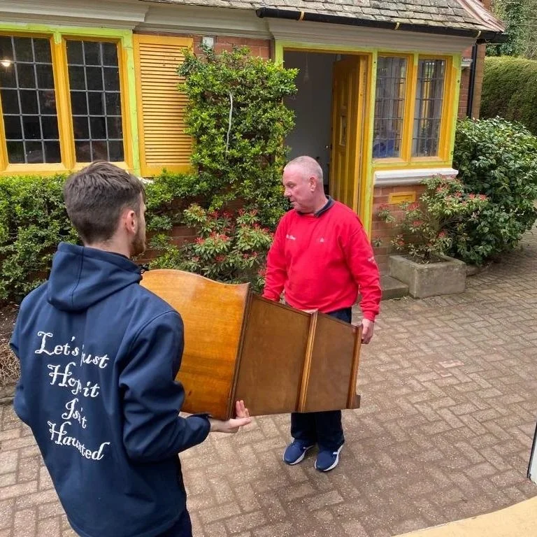 Two professional removalists carrying furniture into a home