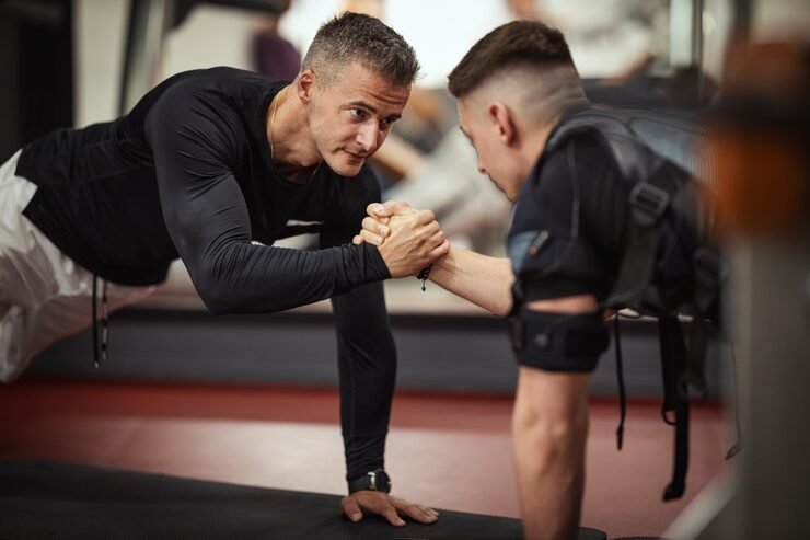 Twee mannen die elkaar de hand schudden en in een plankt-positie zitten in een sportschool.