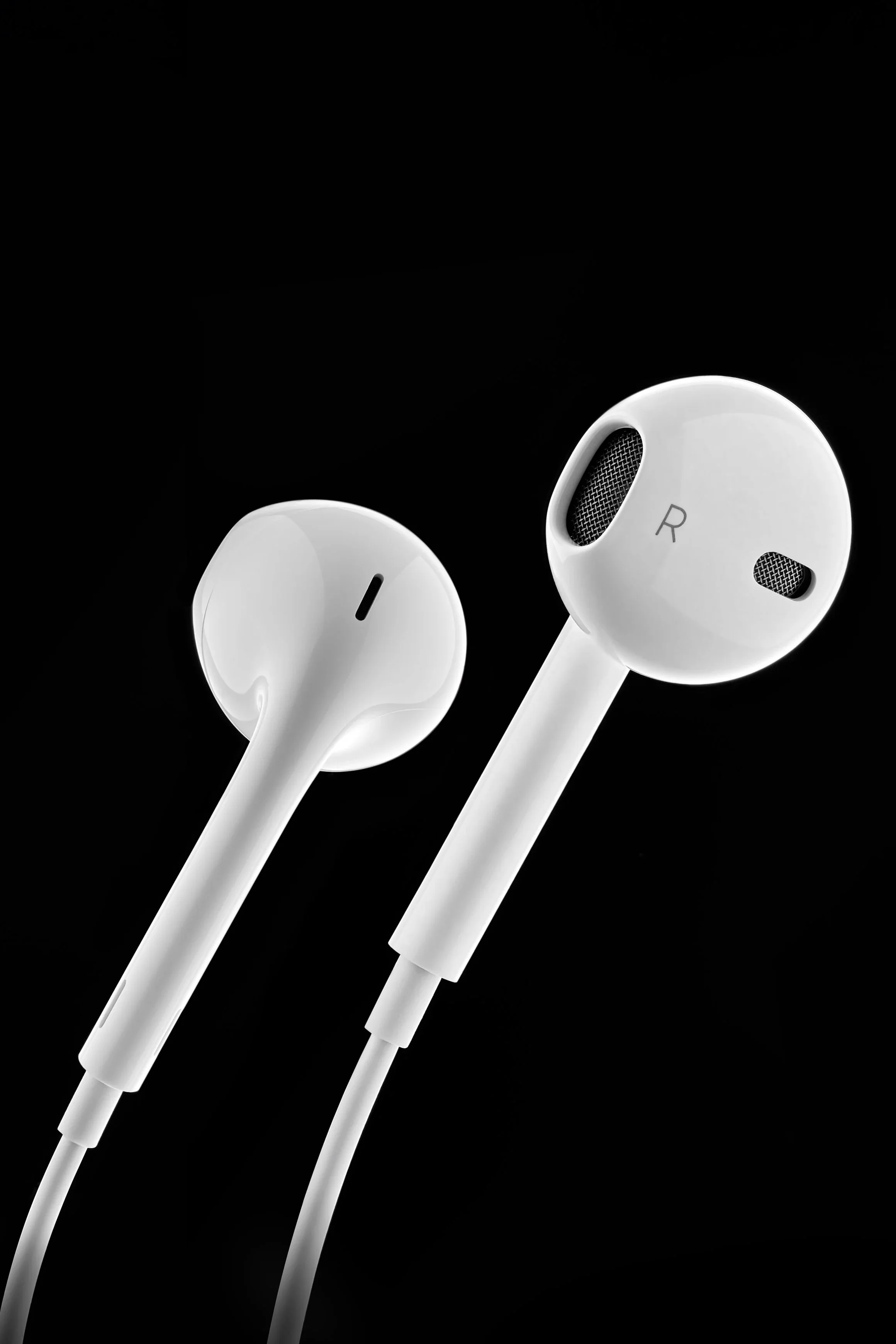 Écouteurs filaires apple blancs contre un arrière-plan noir.