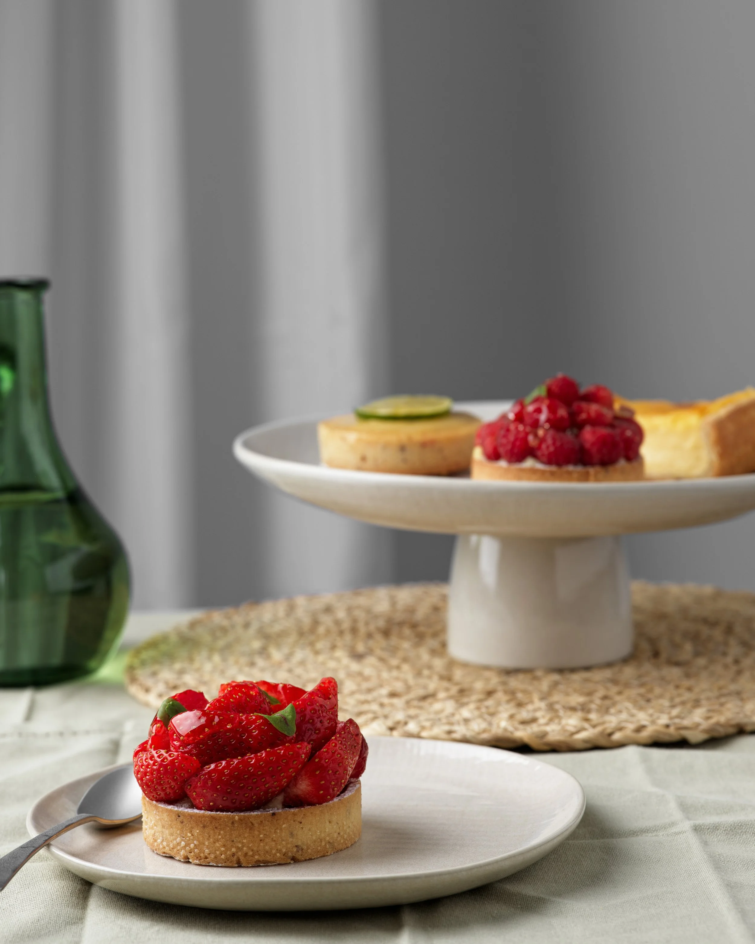 tartelles aux fruits sur une assiette blanche, sur une table avec un décor sobre et élégant
