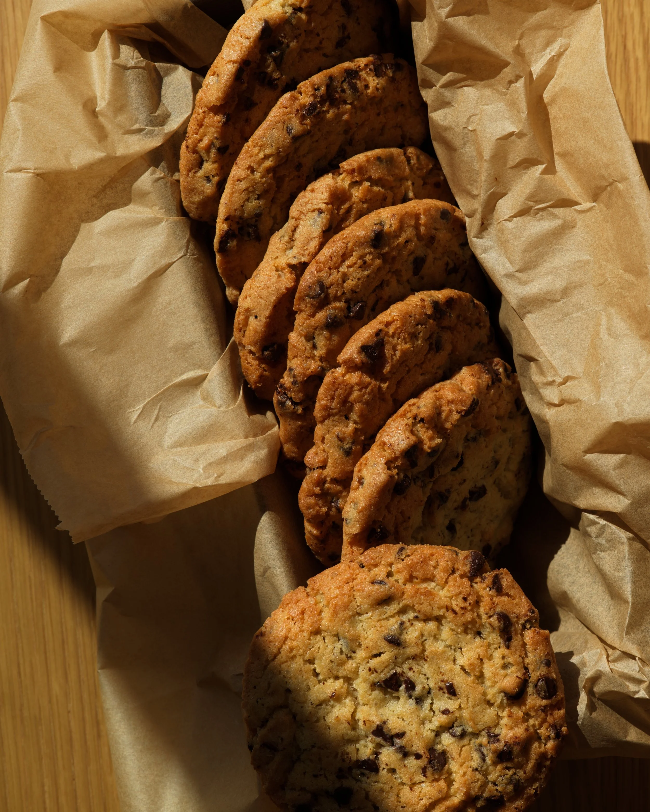 cookies aux pépites de chocolat sur un papier sulfurisé, posé sur une surface en bois.