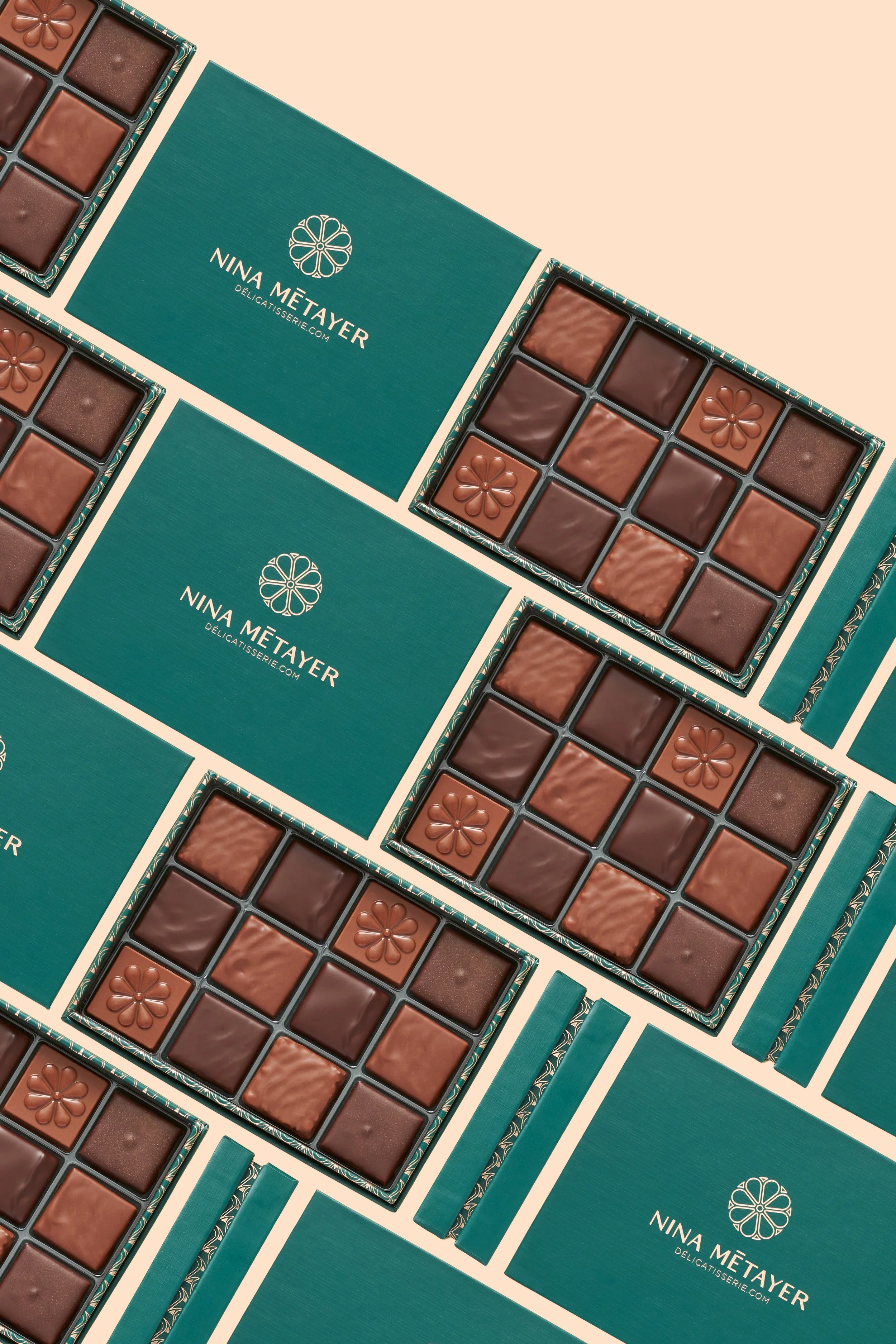 Boîtes de chocolats de Nina Métayer avec des emballages verts et des carrés de chocolat variés.