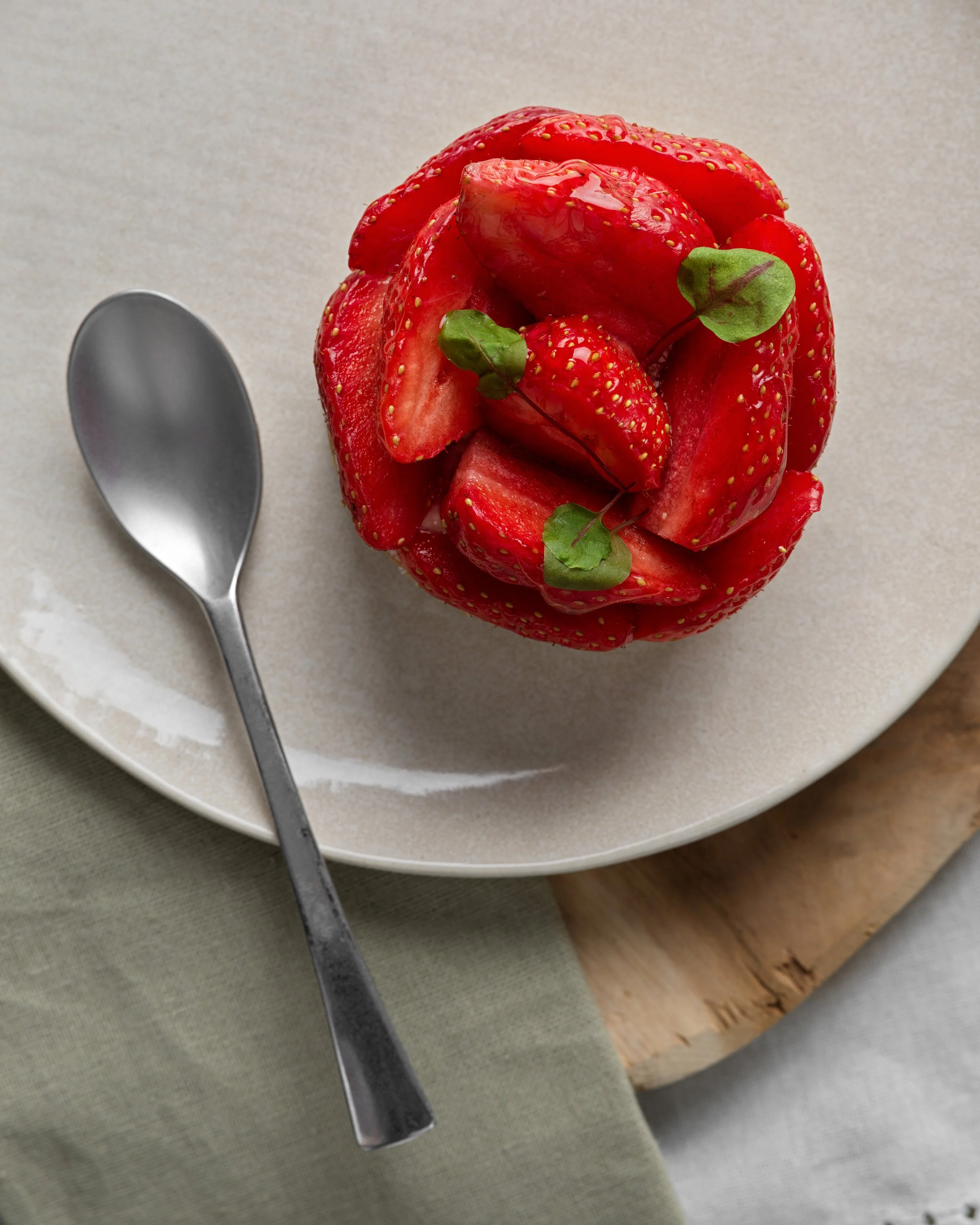 Tartelettes aux Fraises sur une assiette beige, avec une cuillère posée à côté.