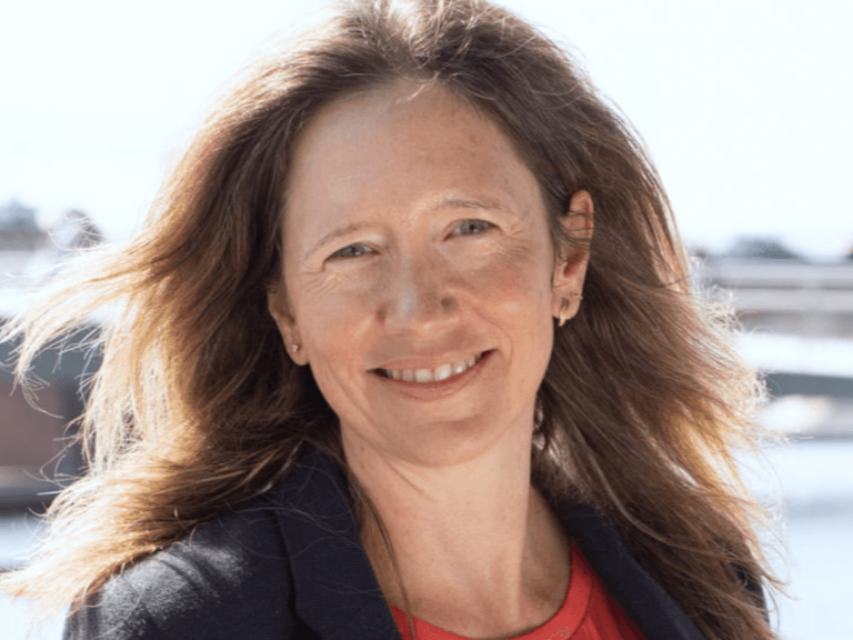 Smiling woman with long red hair outdoors near boats on water