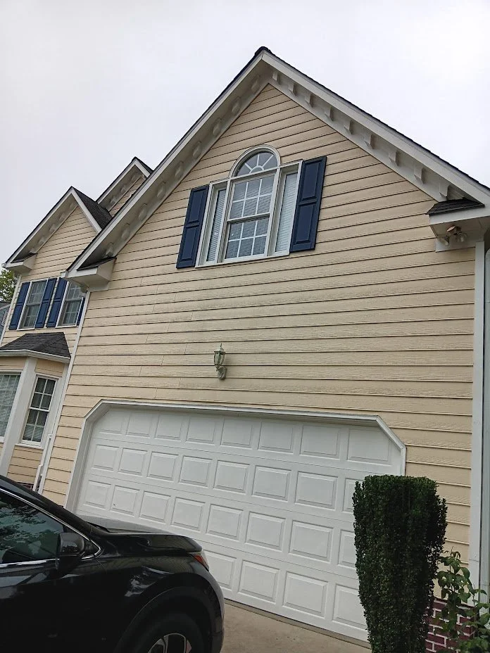 An exterior of a town house with new pale yellow siding