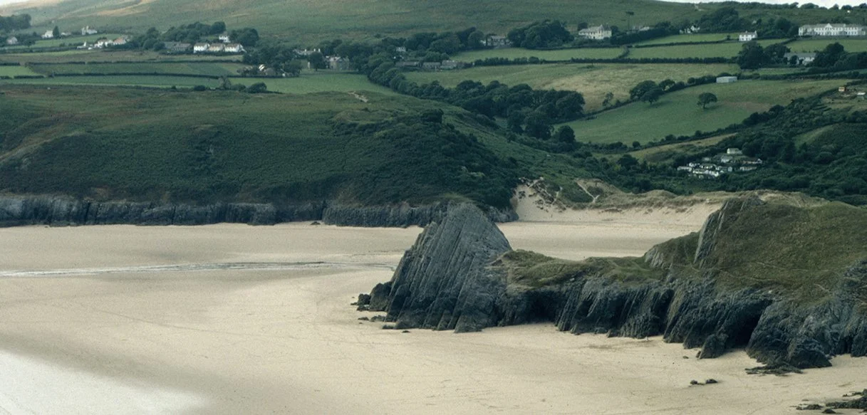 Coastal landscape illustration of Gower alongside details of Welsh stone and digital tools, symbolising the influence of place, heritage, and craftsmanship on Rhys Bevan’s work.