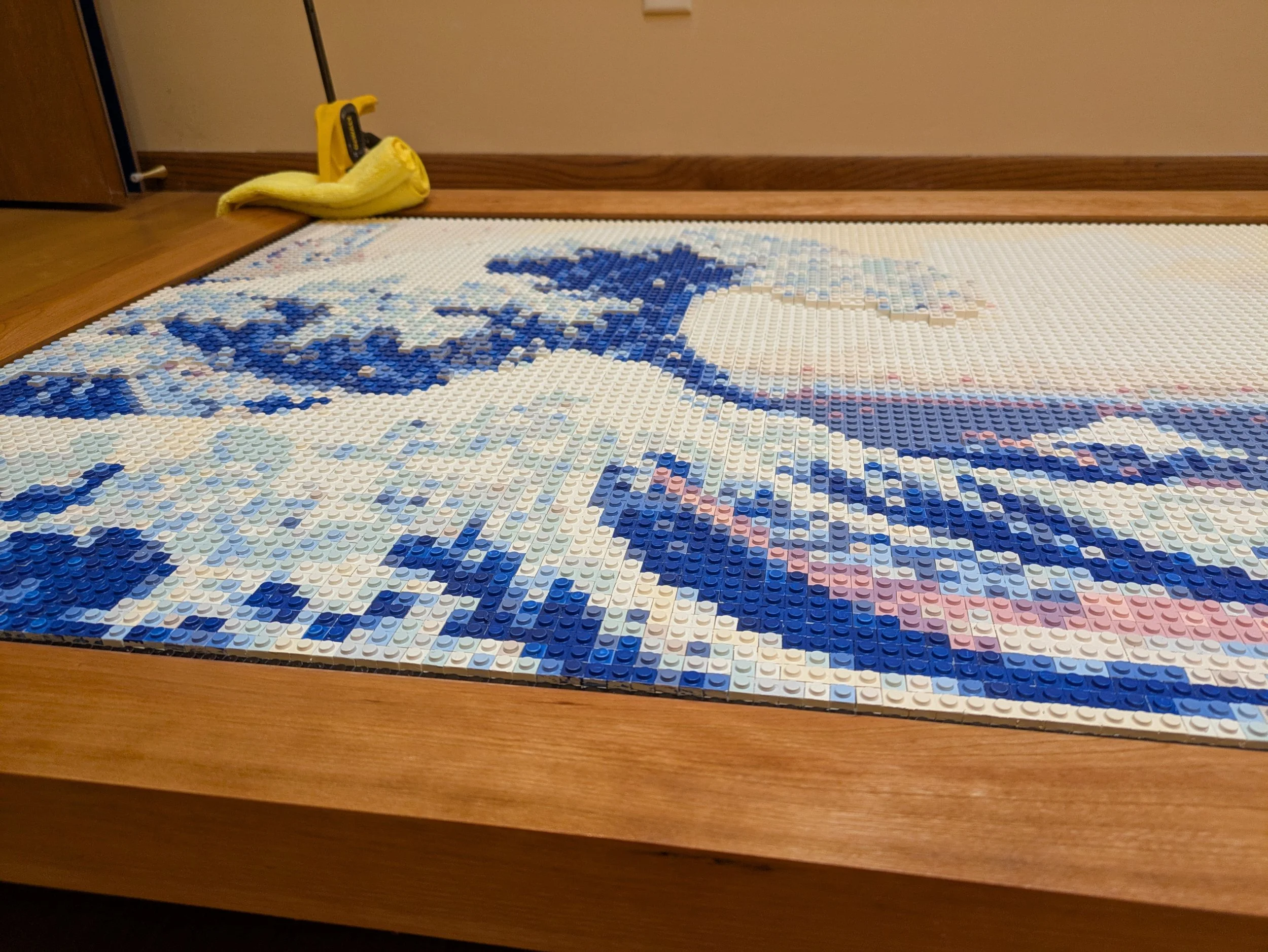 A mosaic of the Great Wave off Kanagawa made from LEGO bricks on a wooden table