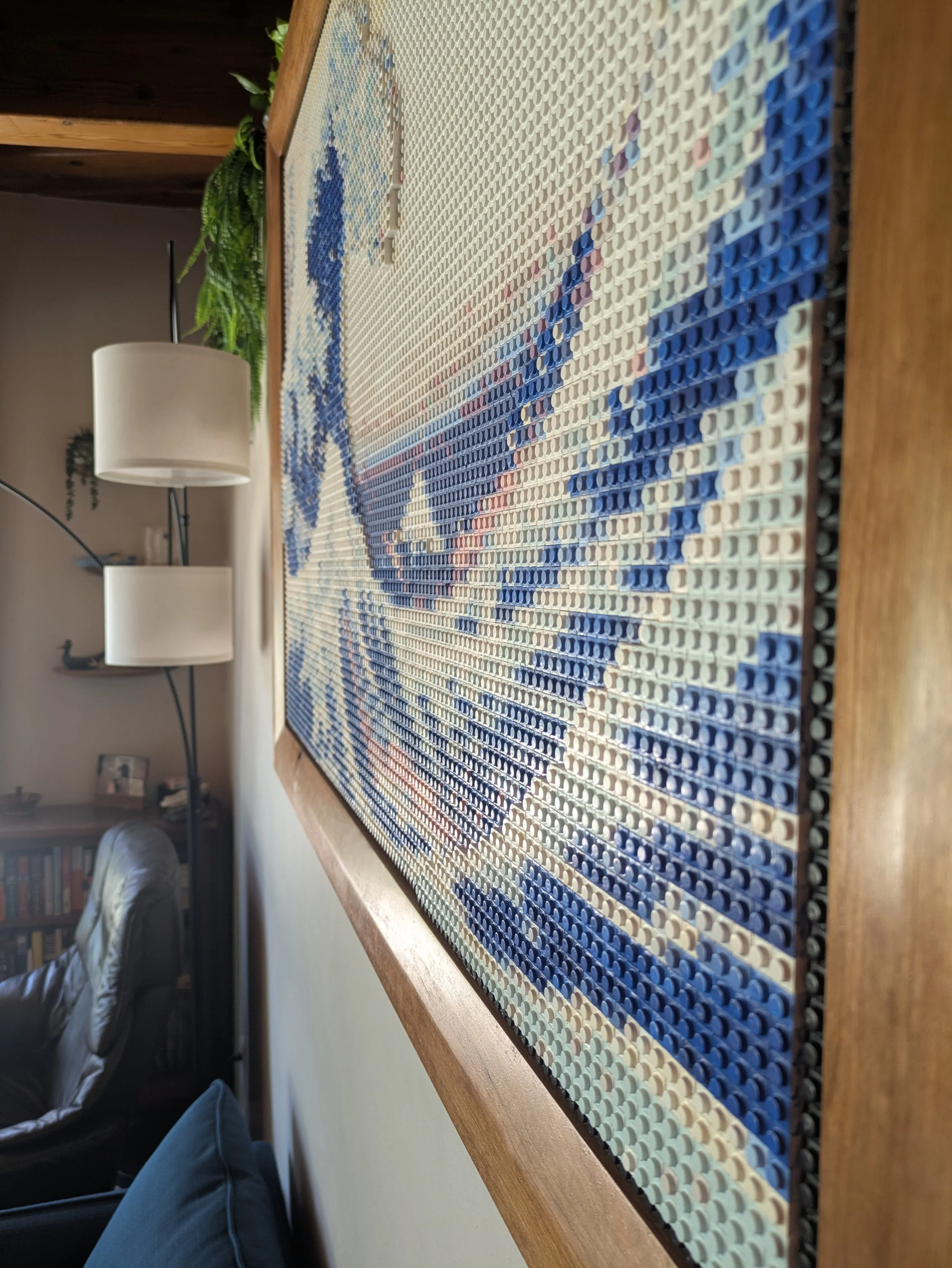 Close-up of a LEGO mosaic artwork of the Great Wave off Kanagawa on a wooden framed board.
