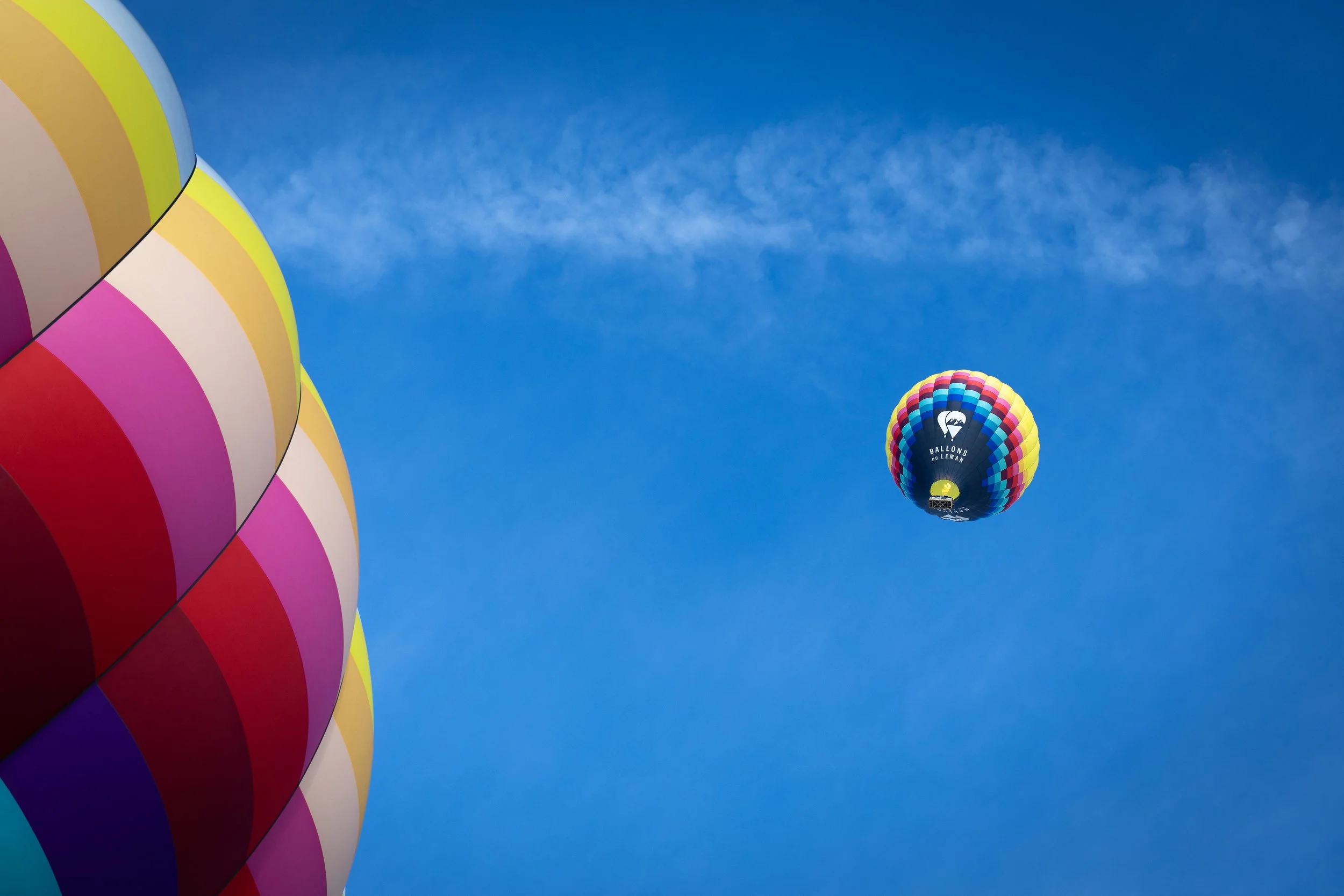 Ein farbenfroher Heißluftballon im Himmel, umgeben von blauer Wolkenfreiheit.