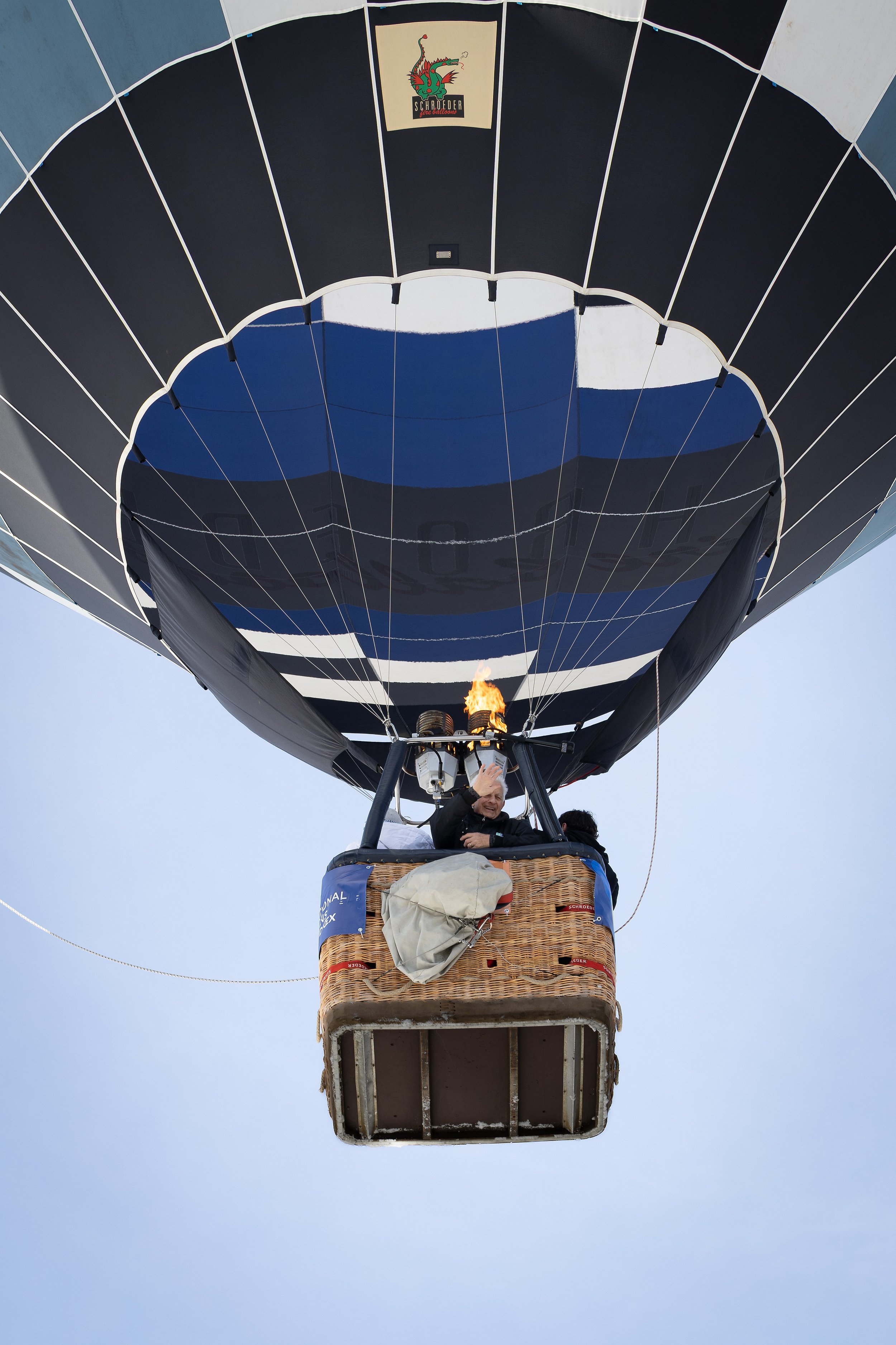 Heißluftballon fliegt in den Himmel, Pilot winkt, under the basket.