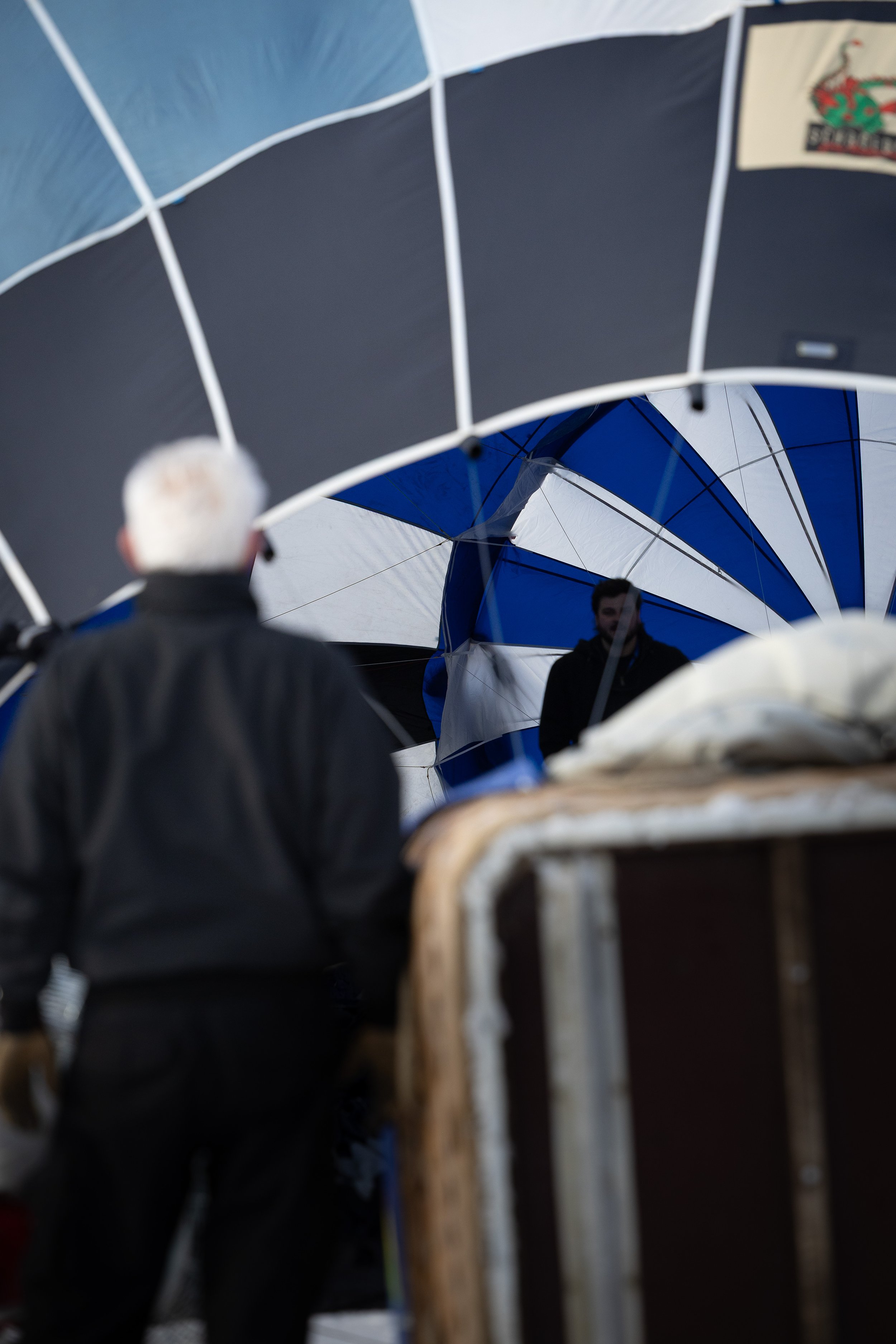 Team beim Aufblasen eines Ballons vor dem Start. Blick in die Ballonhülle mit blauen, weißen und schwarzen Segeln. Eventshooting.