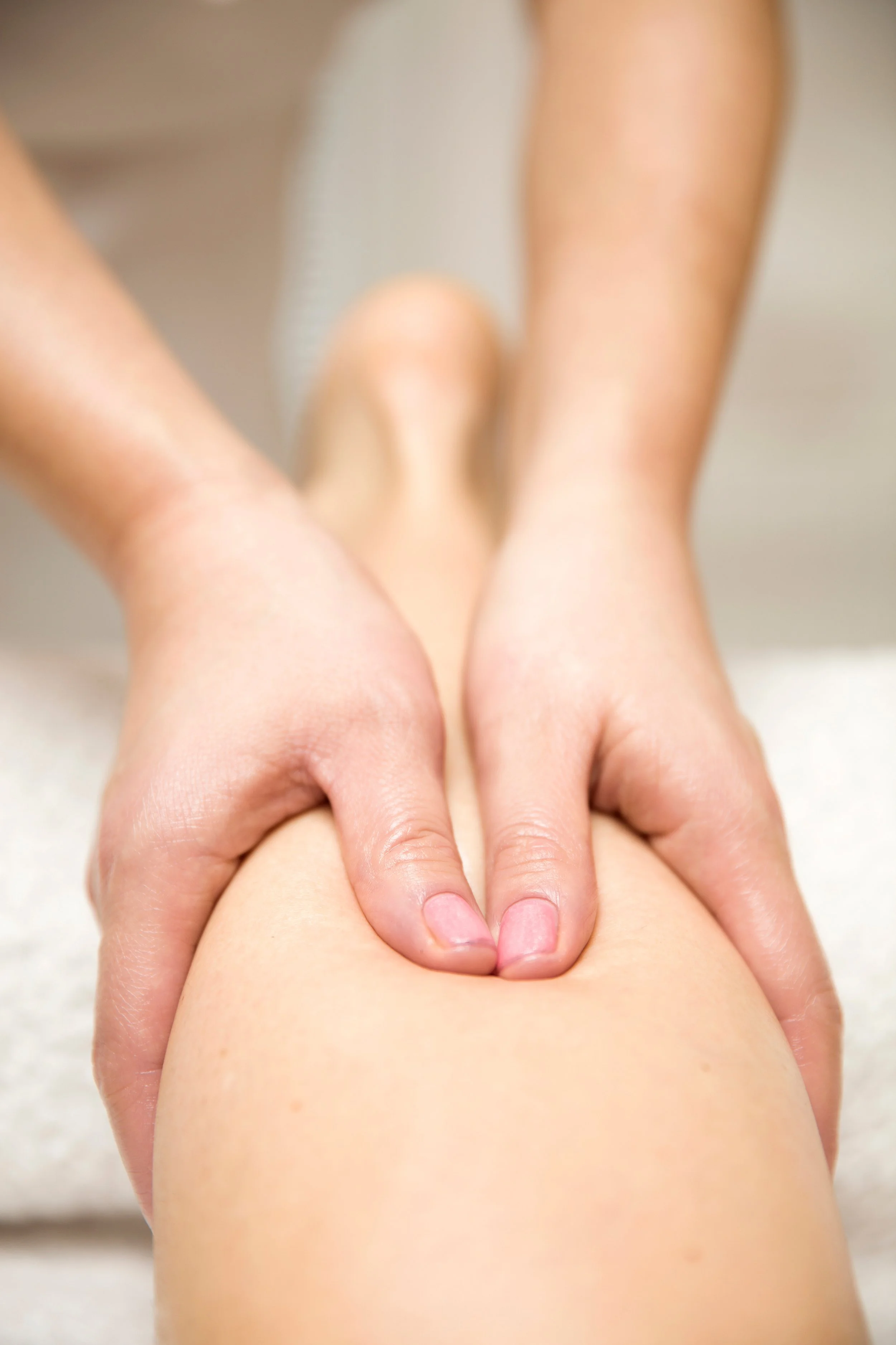 Close-up of a massage therapist applying pressure on a person's thigh during a massage session.